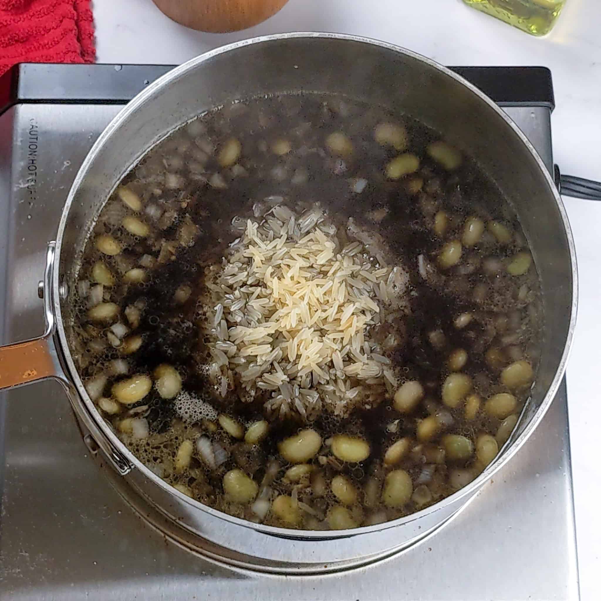 Top view of the rice hill poking out in the middle of the pot of beans and broth.