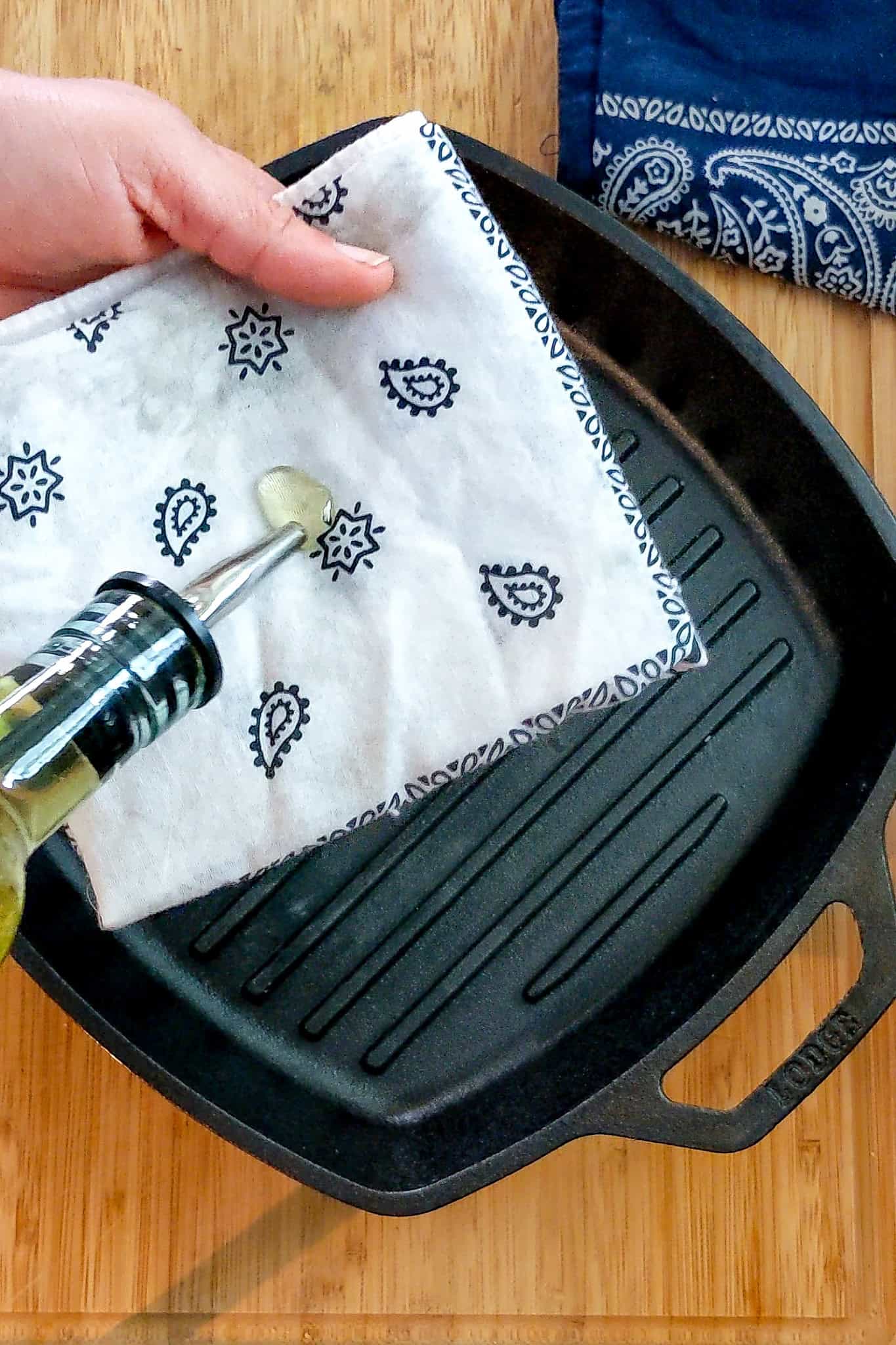 oil being poured onto folded clean bandana above grill pan to season.