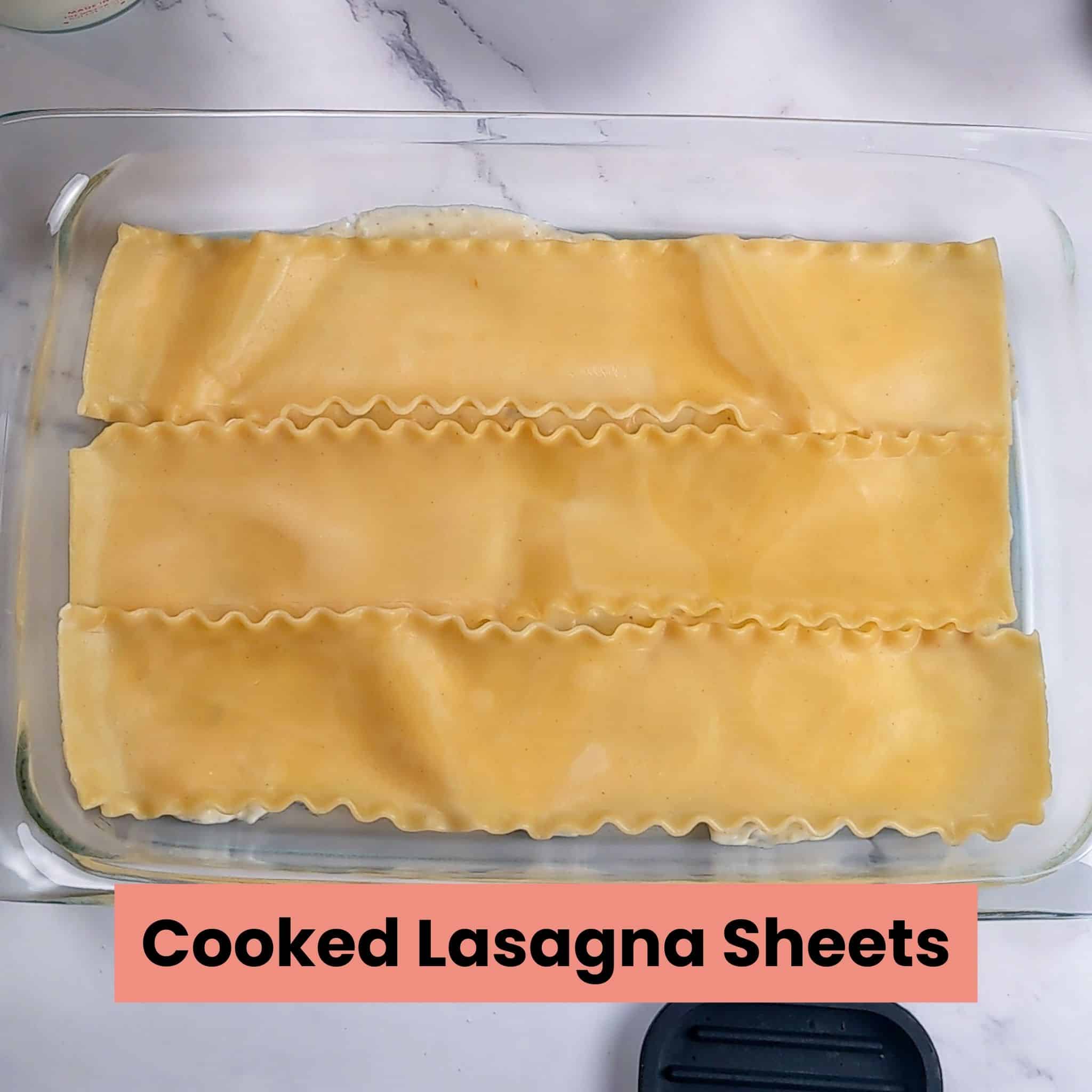 cooked lasagna sheets in a glass rectangle baking dish.