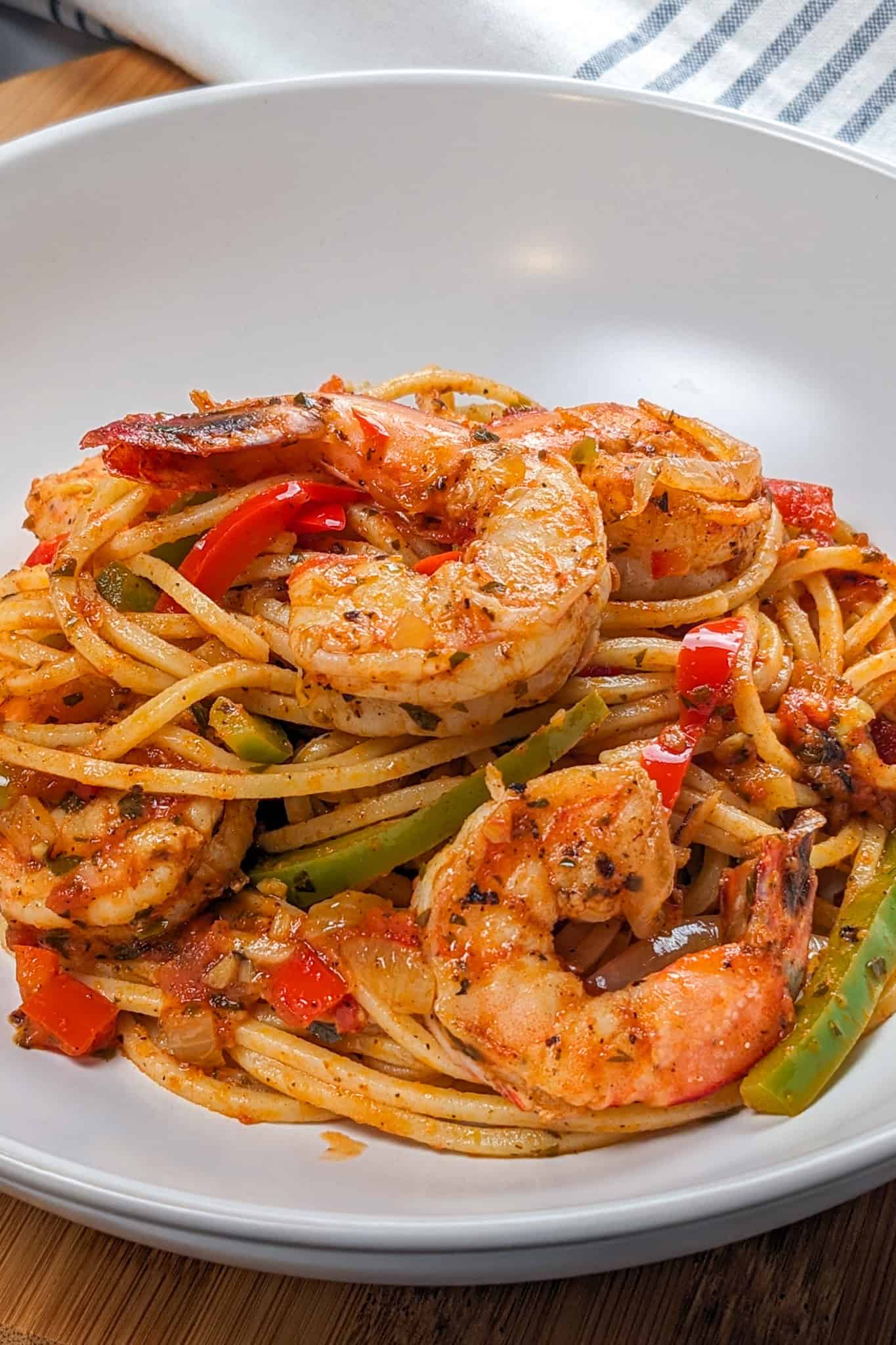 Close-up of the Haitian-style spaghetti with shrimp and creole sauce in a wide-rim pasta bowl.