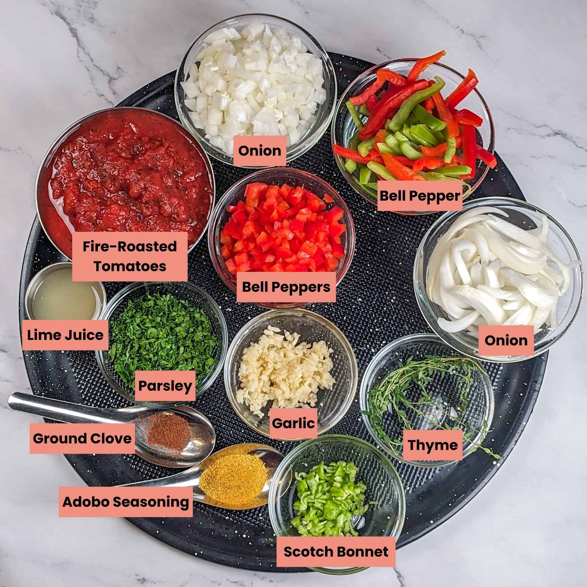 The healthy Haitian-style Creole spicy shrimp pasta ingredients in containers on a large round Pizza pan.