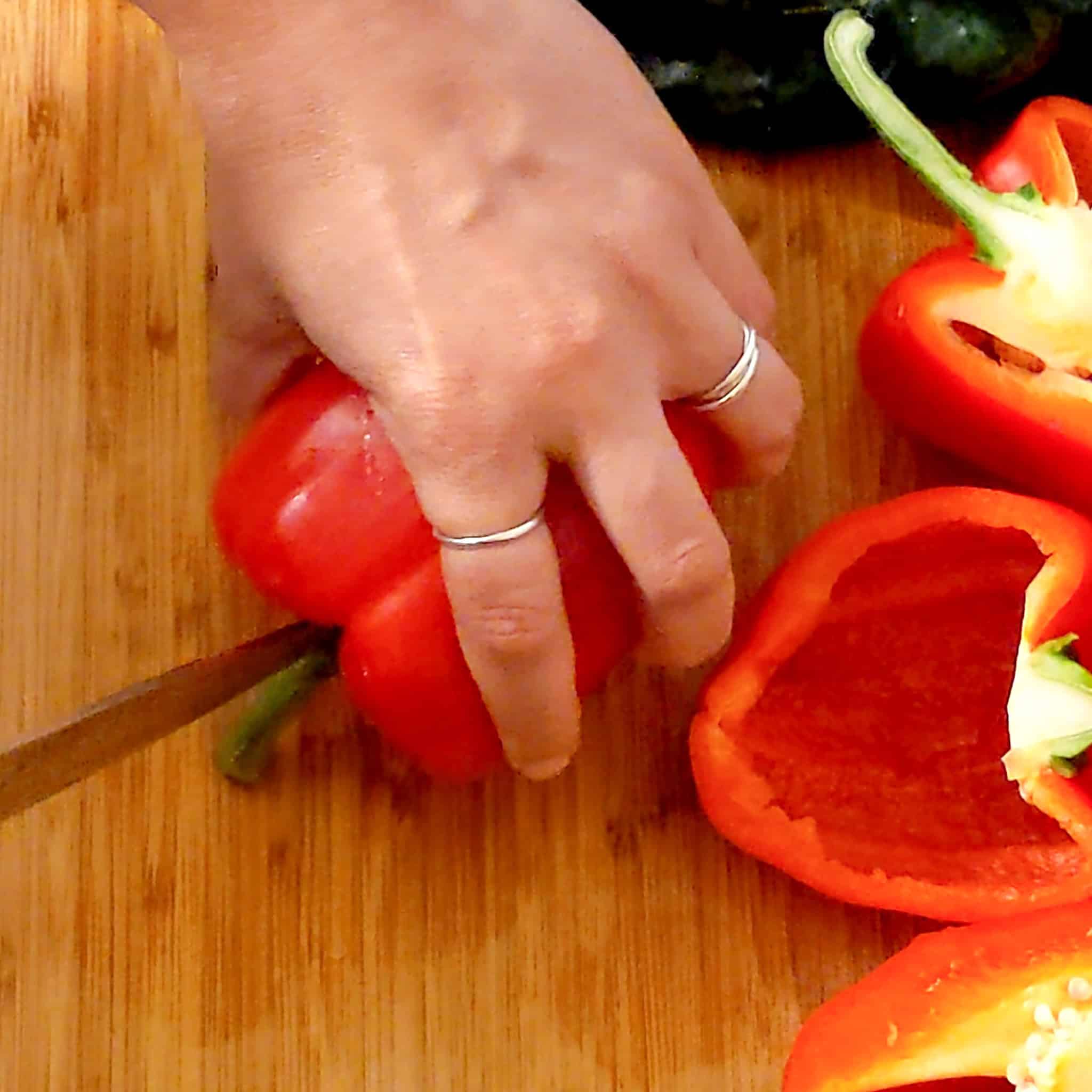 a knife slicing the stem of the bell pepper into two.