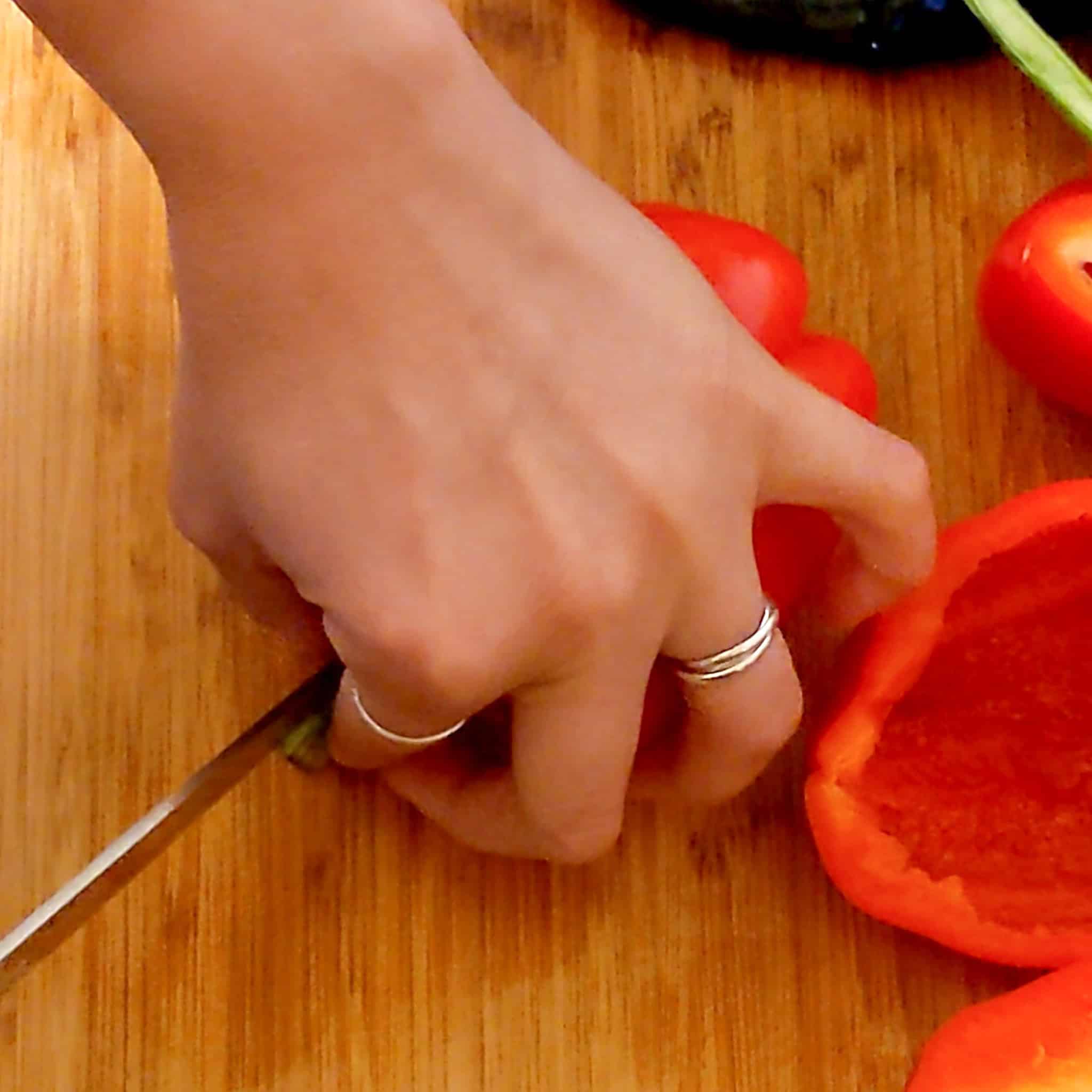 two fingers pinching the stem to hold in place as the knife finishes cutting through.