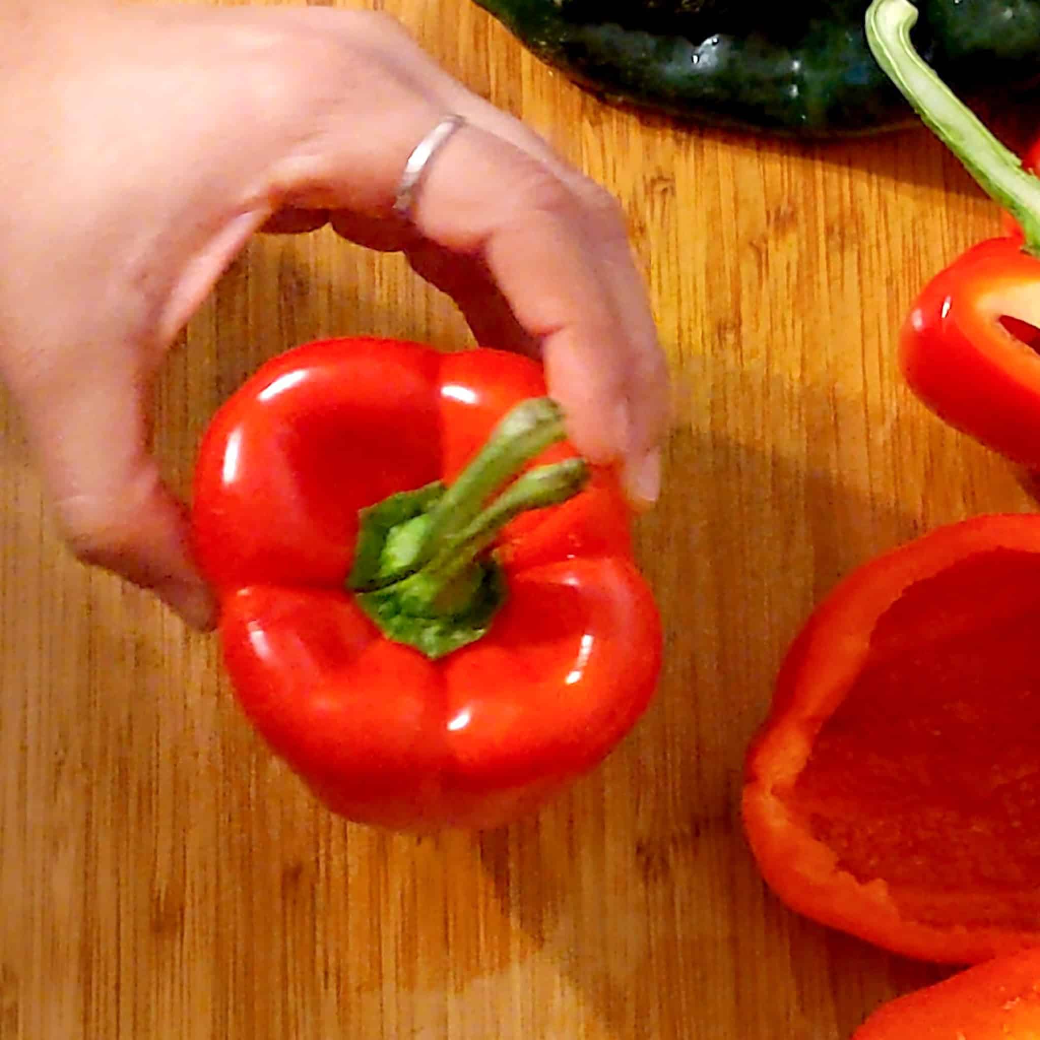 a hand holding bell pepper upright showcasing the split stem.