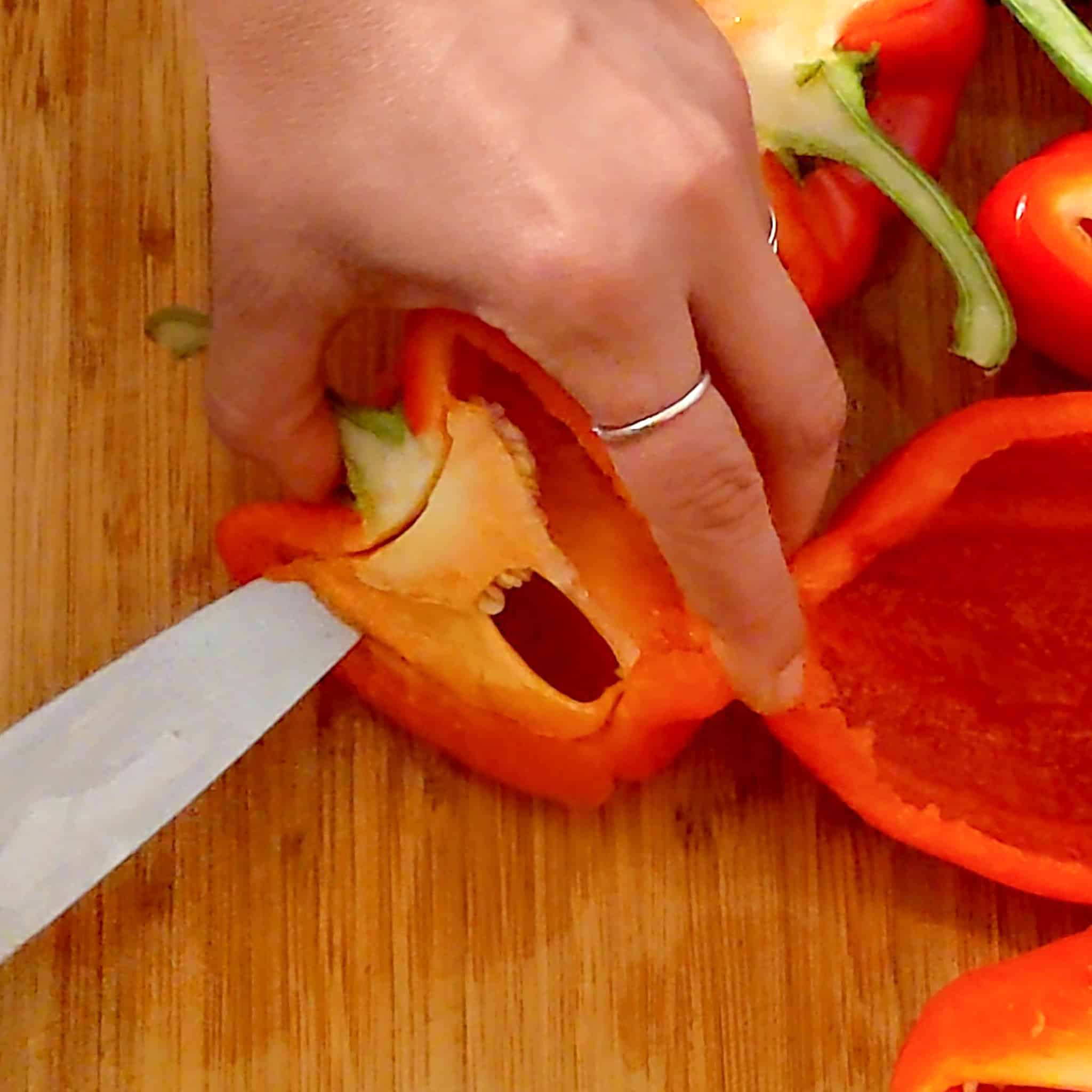 A sharp knife continuing to cut the pith and core from the Flesh of the bell pepper.