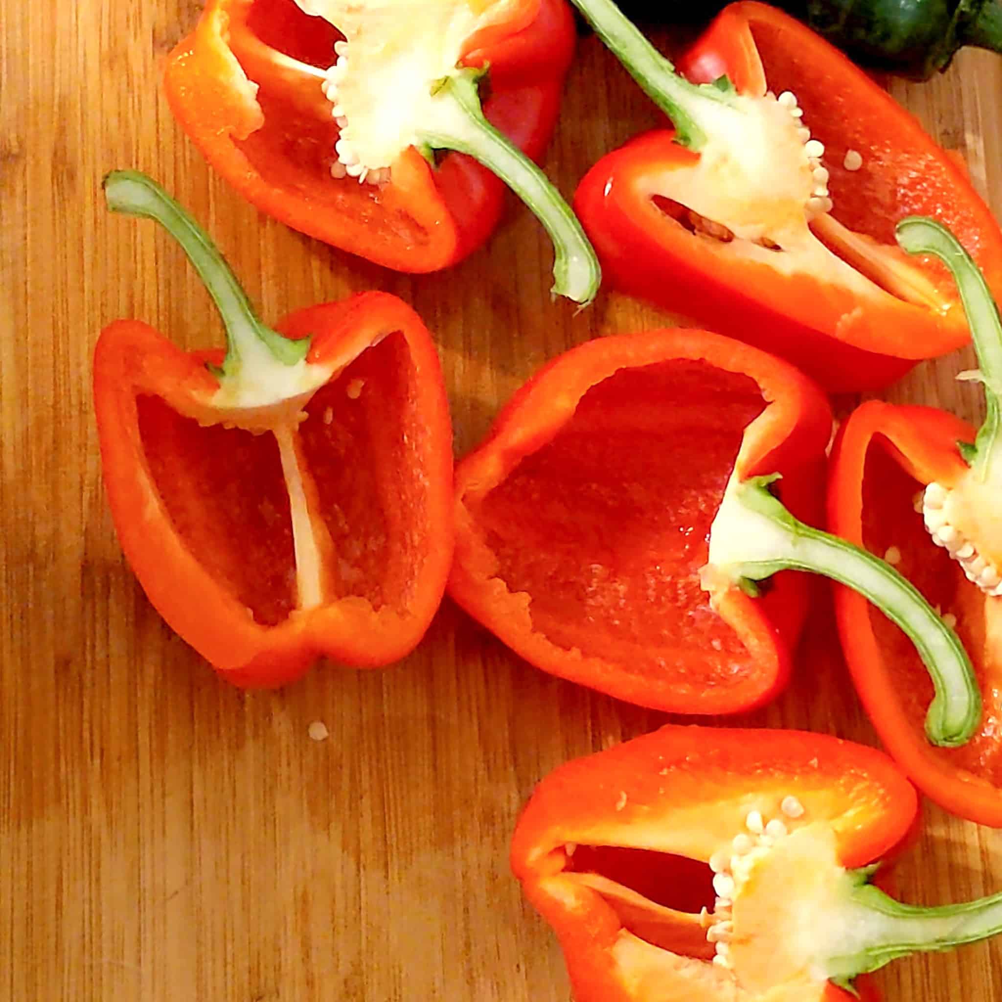 The cored and seeded bell pepper rests on the cutting board, along with other halved bell peppers.