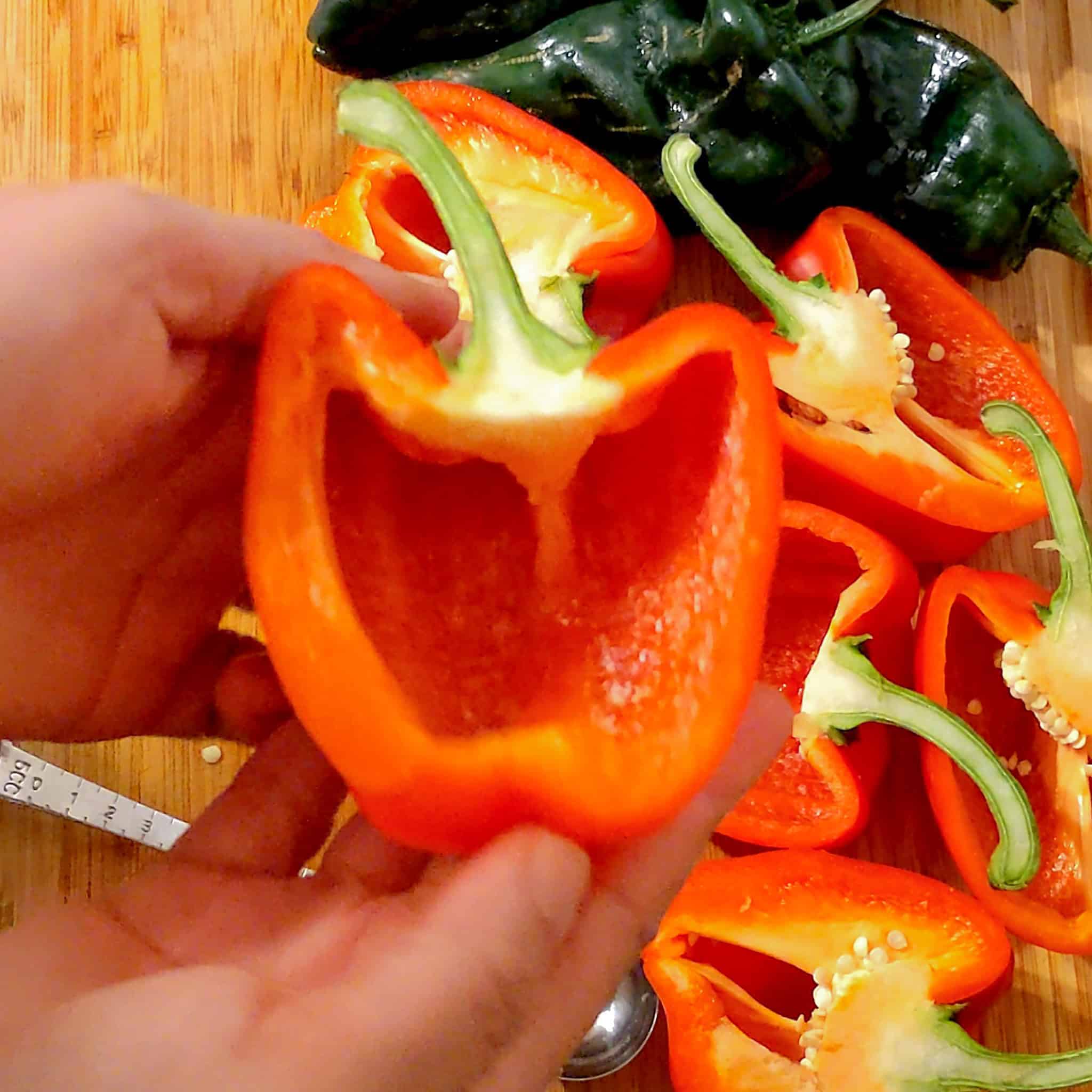 Two hands showcasing the bell pepper with the pith seed and core removed for Cooking with Sweet Peppers.