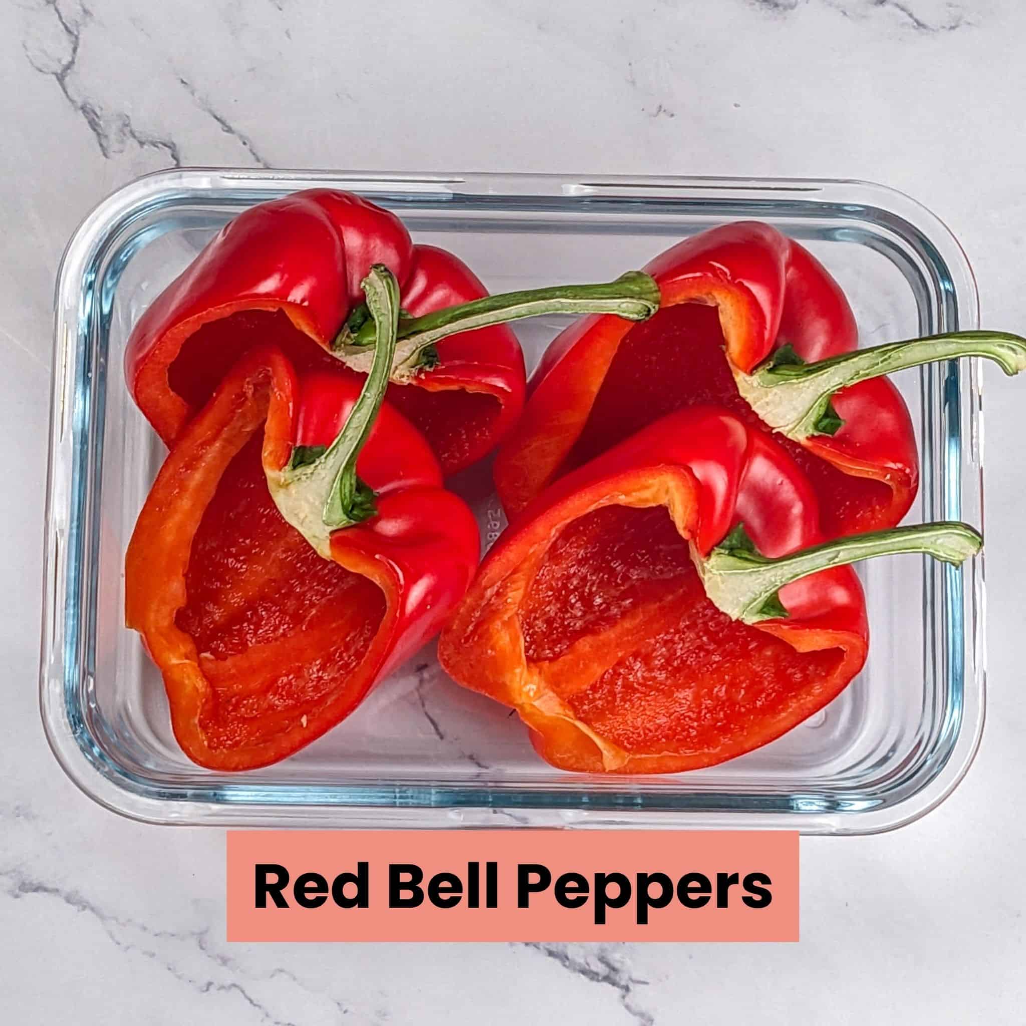 Halved red bell peppers in a rectangular glass dish.