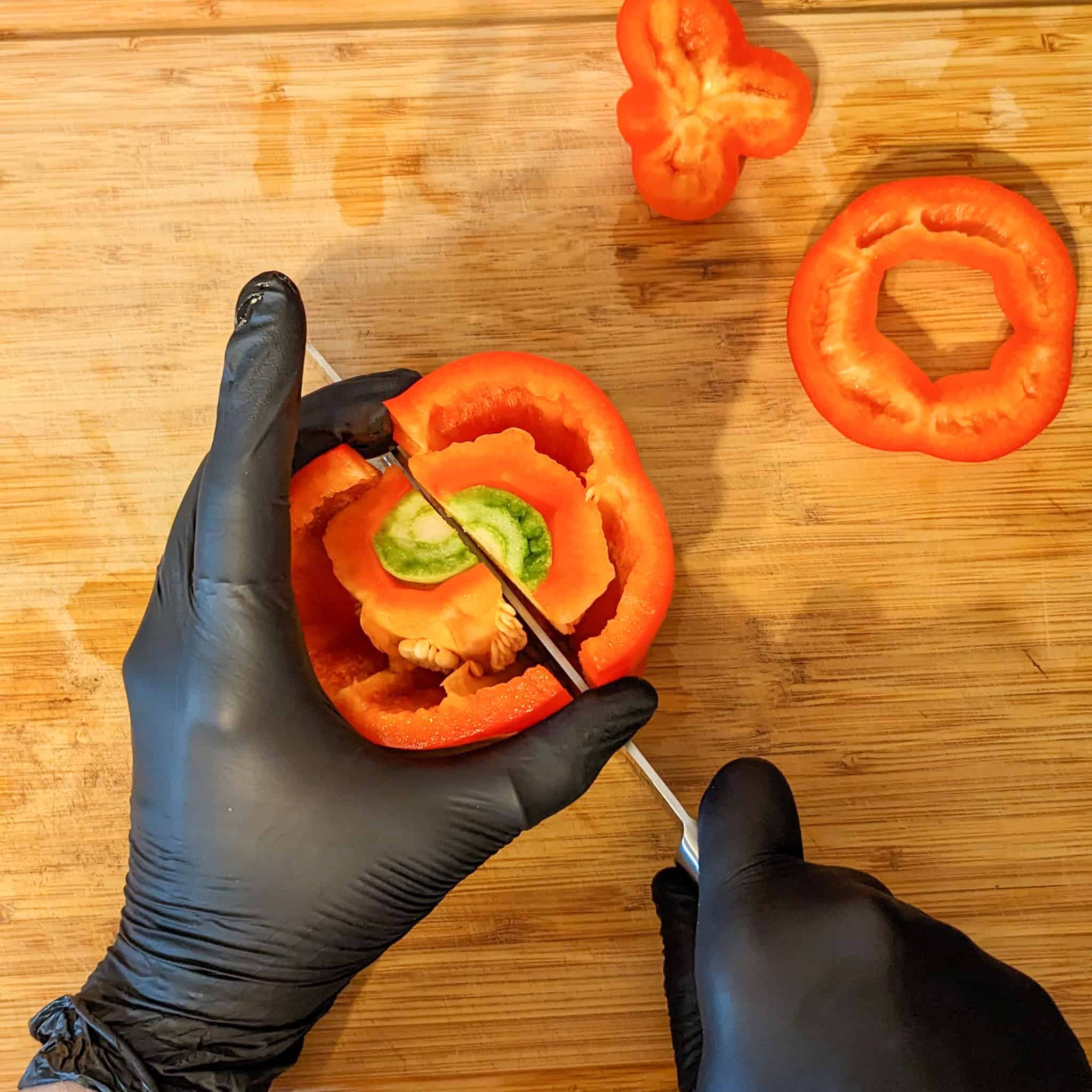 A knife cuts the pepper in half.