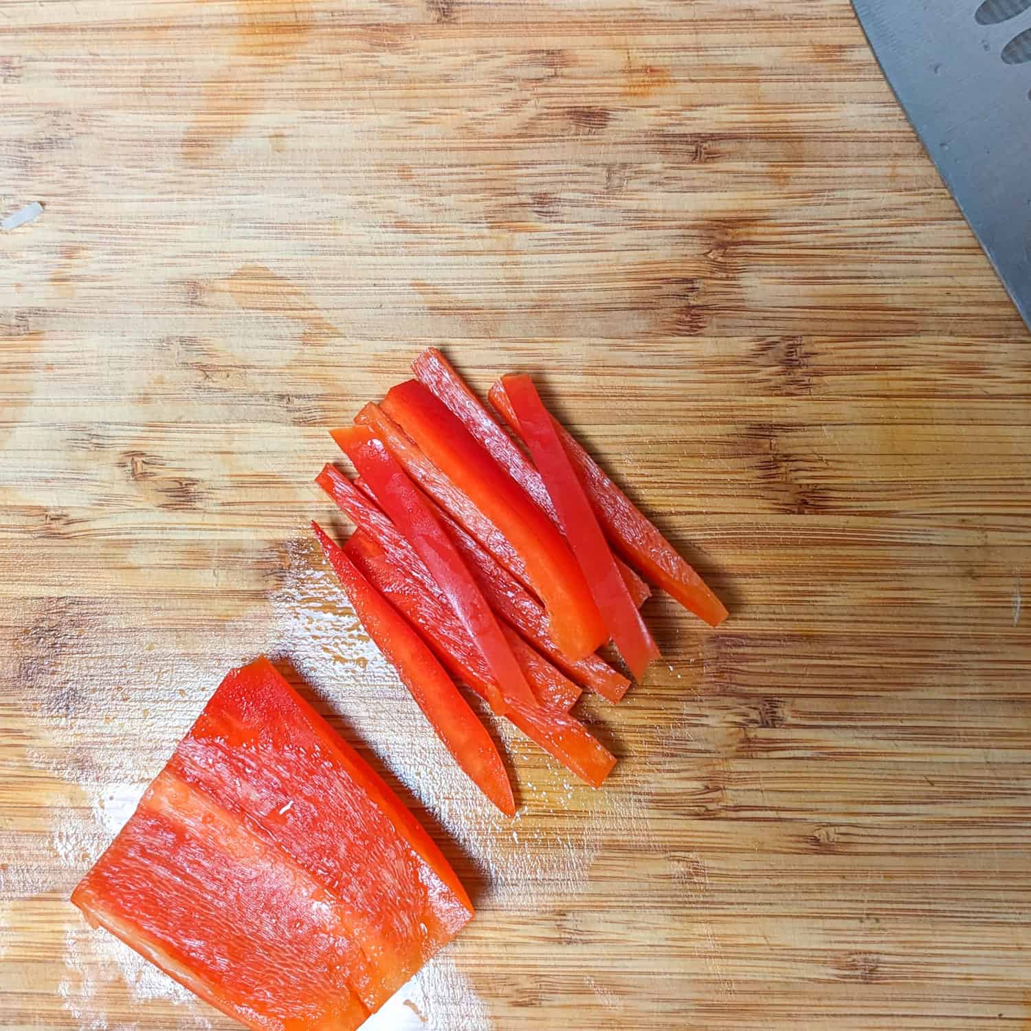 bell peppers cut into batonnets next to a piece of bell pepper with all of the white pith removed.