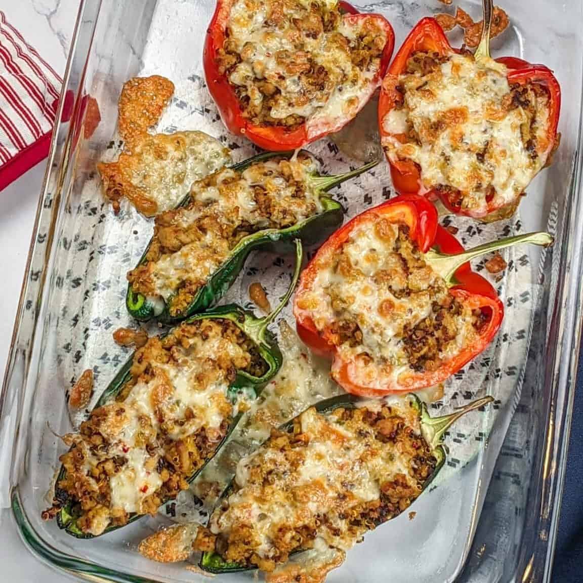 Baked stuffed peppers are resting on the countertop in a glass 13x9-in baking dish.