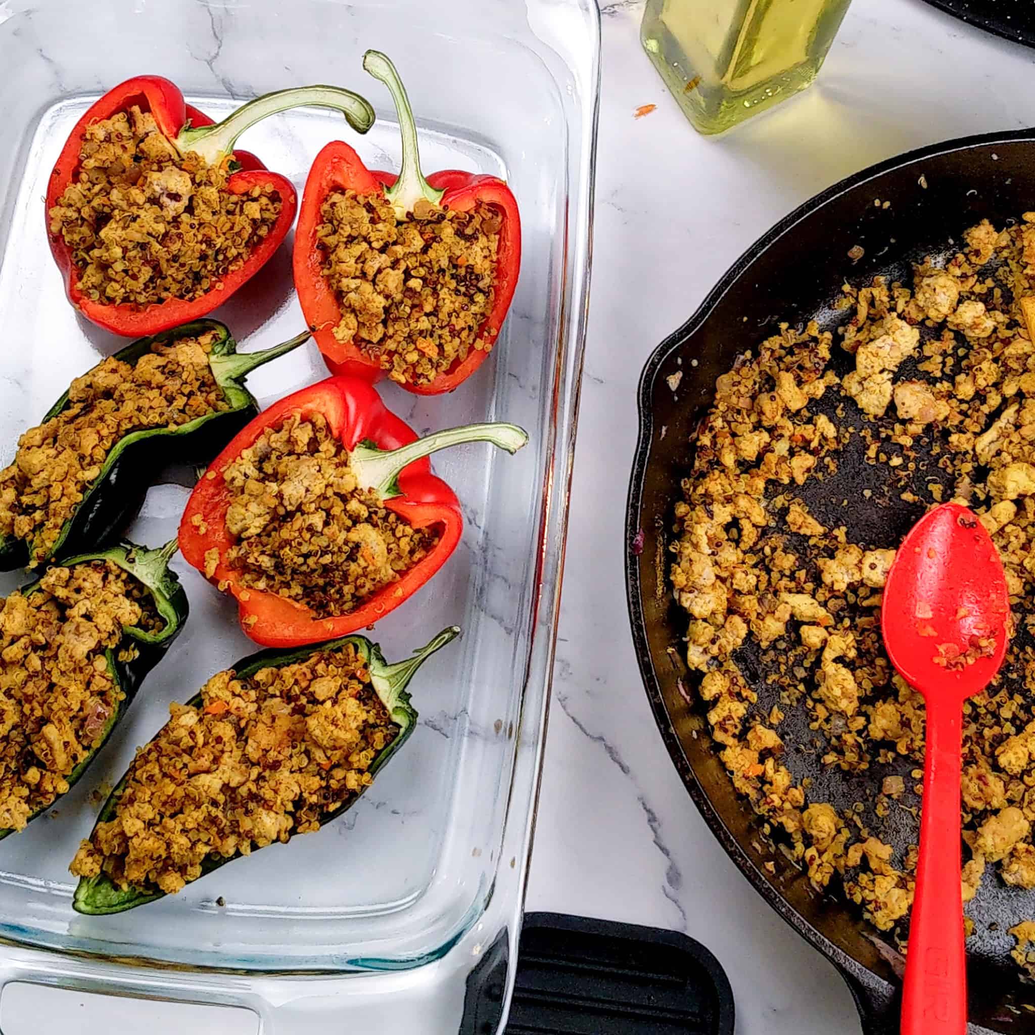 Ground turkey and quinoa are stuffed into bell peppers and poblanos that have been cut in half vertically with the stem still on. They are then placed in a glass 13 x 9 baking dish next to a cast iron of extra ground turkey and quinoa.