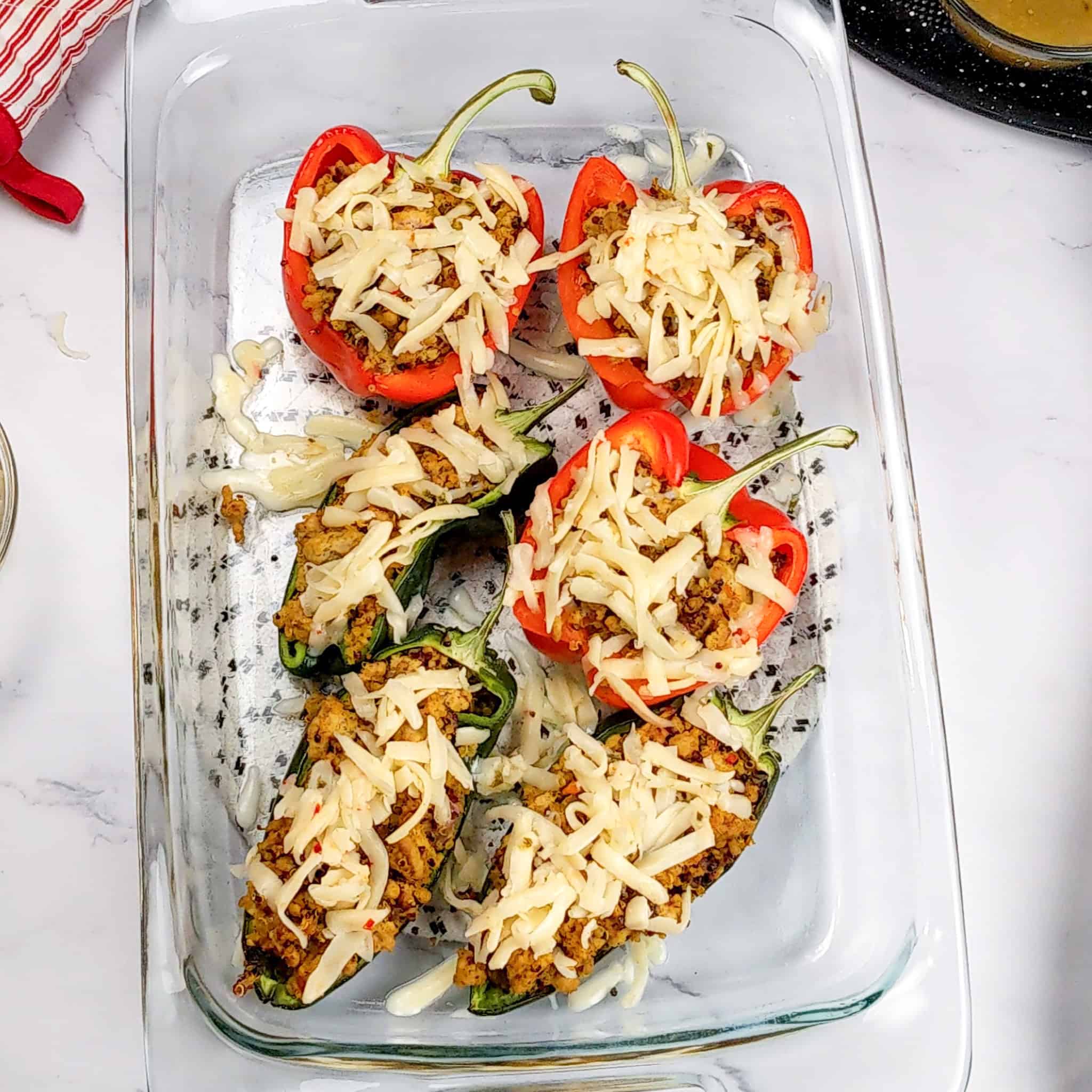 The glass baking dish of stuffed peppers covered with shredded cheese.