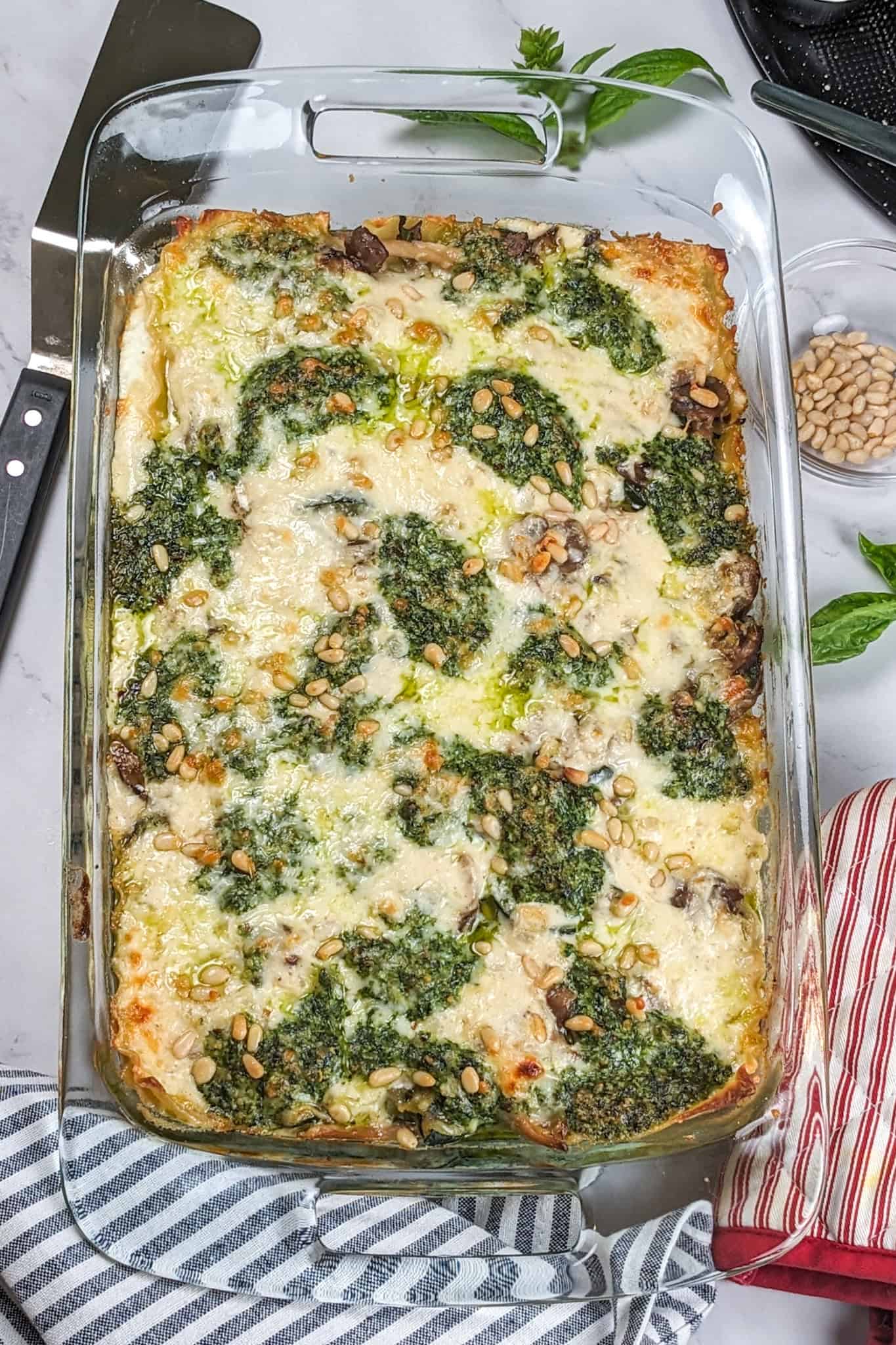 top view of the Creamy Spinach Pesto Mushroom Lasagna in a 13 by 9 glass pyrex baking dish.