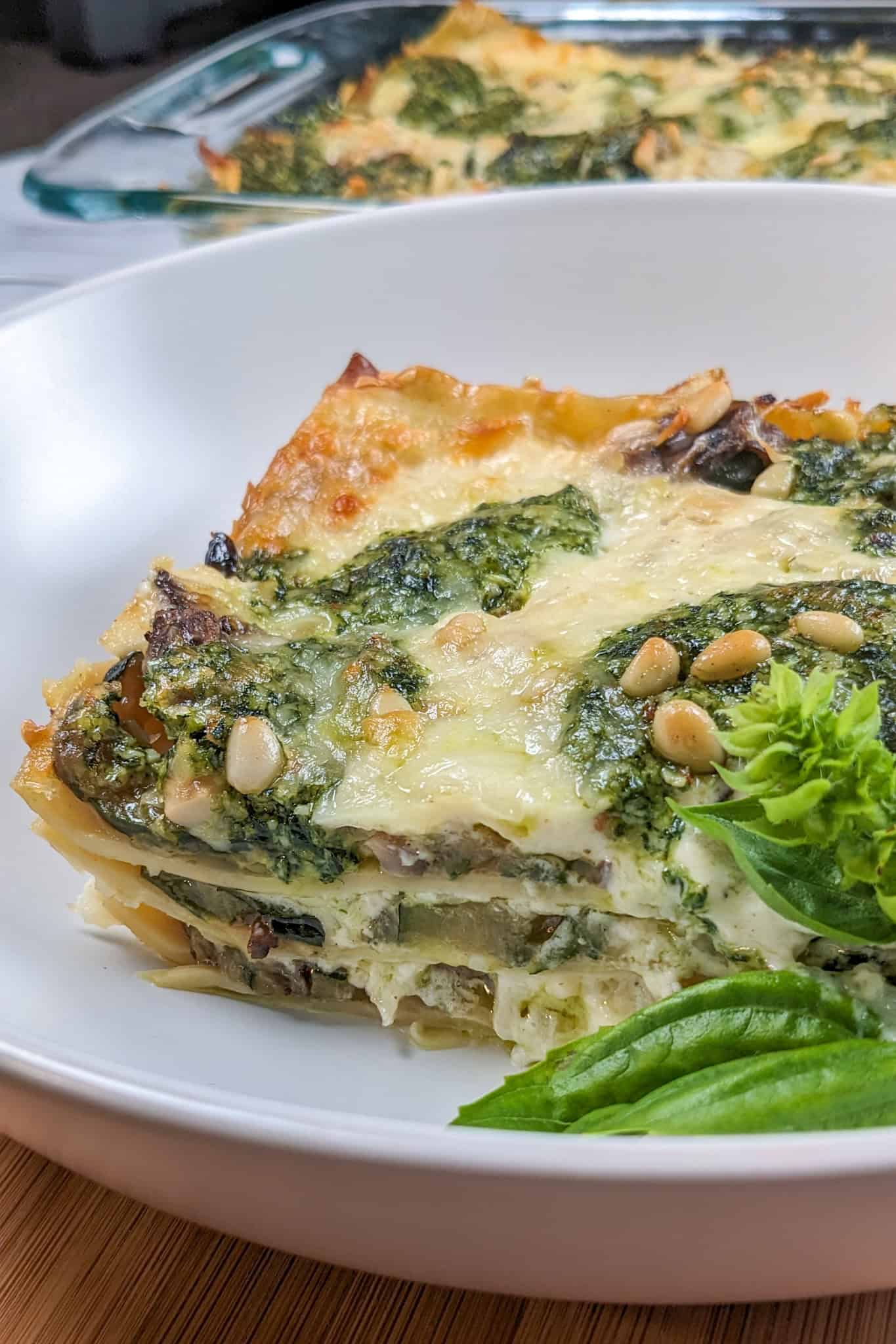 side view of the Creamy Spinach Pesto Mushroom Lasagna in a wide rim pasta bowl.