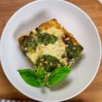 top view of the Creamy Spinach Pesto Mushroom Lasagna in a wide rim bowl garnished with basil.