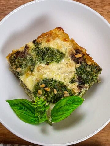 top view of the Creamy Spinach Pesto Mushroom Lasagna in a wide rim bowl garnished with basil.