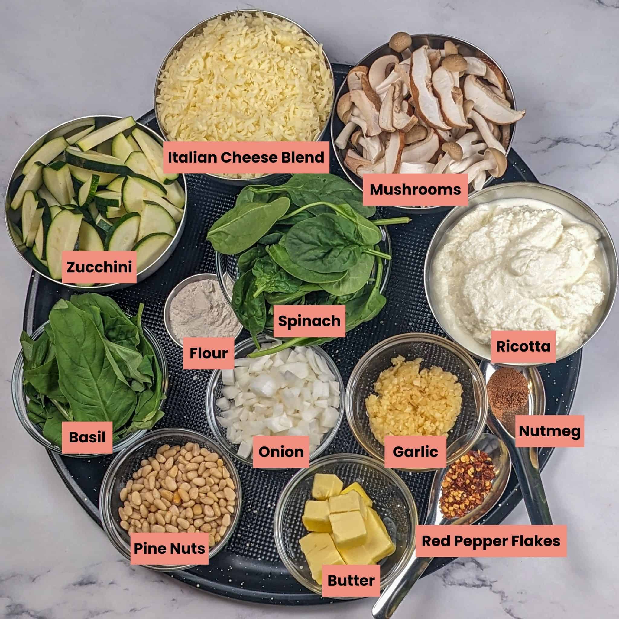 ingredients for the Creamy Spinach Pesto Mushroom Lasagna in a large round pizza pan.