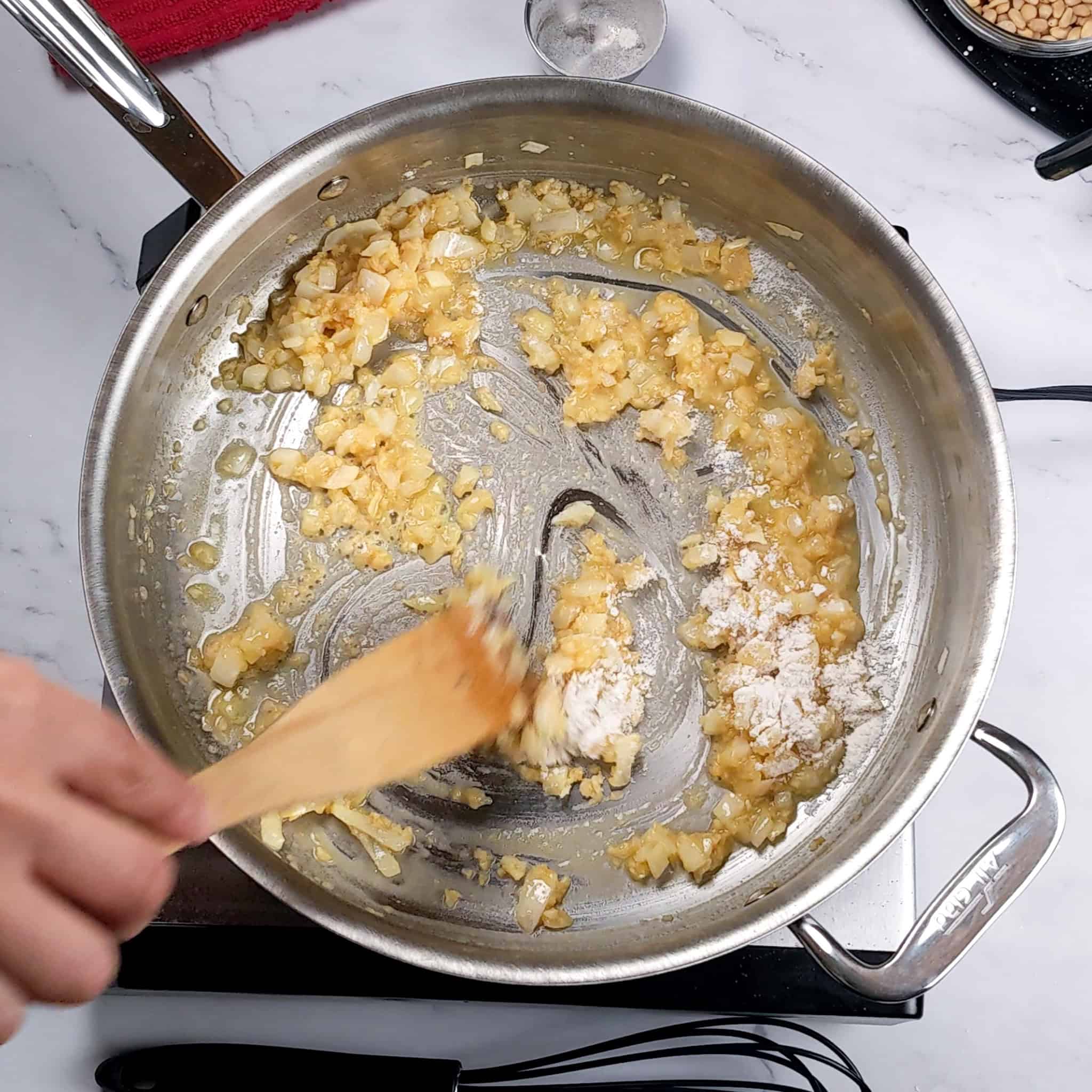 browned onion and garlic being mixed with flour with a wooden spatula.