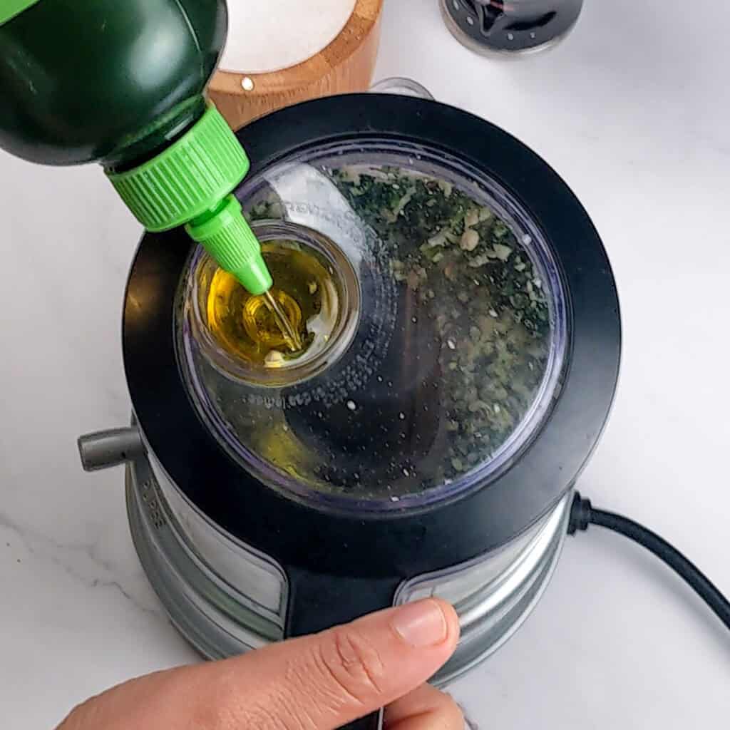 Garza olive oil is drizzled into the basin of the KitchenAid food chopper food processor.