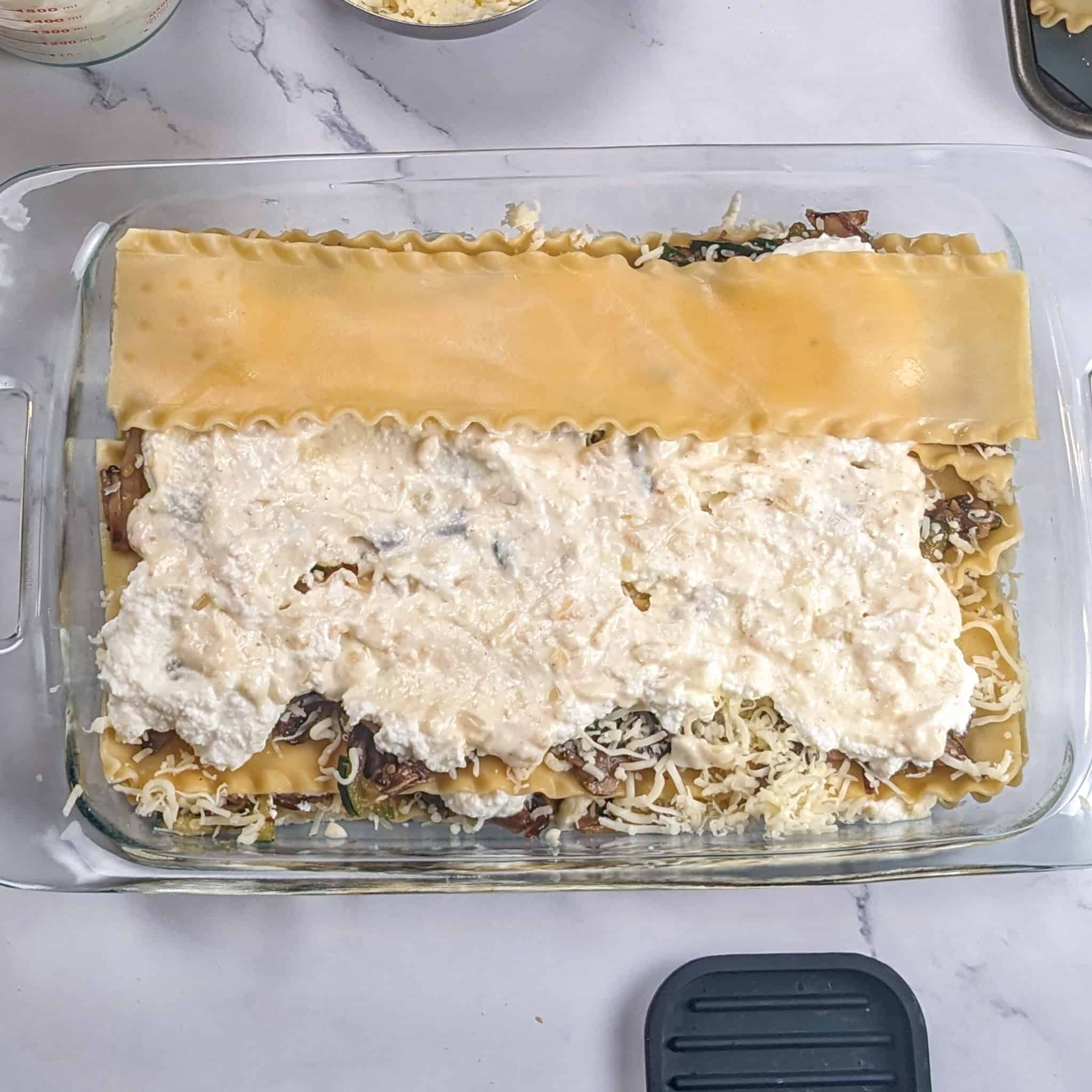 Another layer of lasagna sheets is being added.