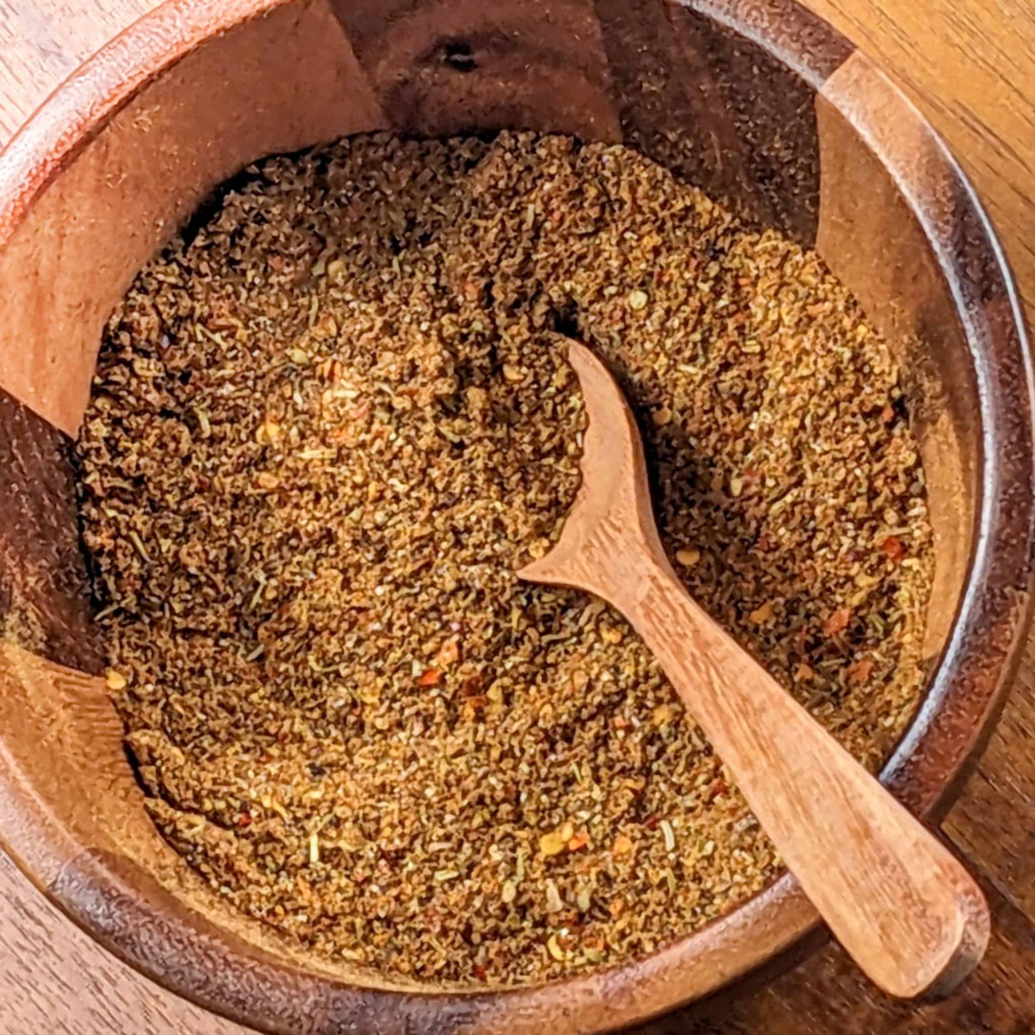 spicy all purpose seasoning blend in a wooden bowl mixer with wooden spoon.