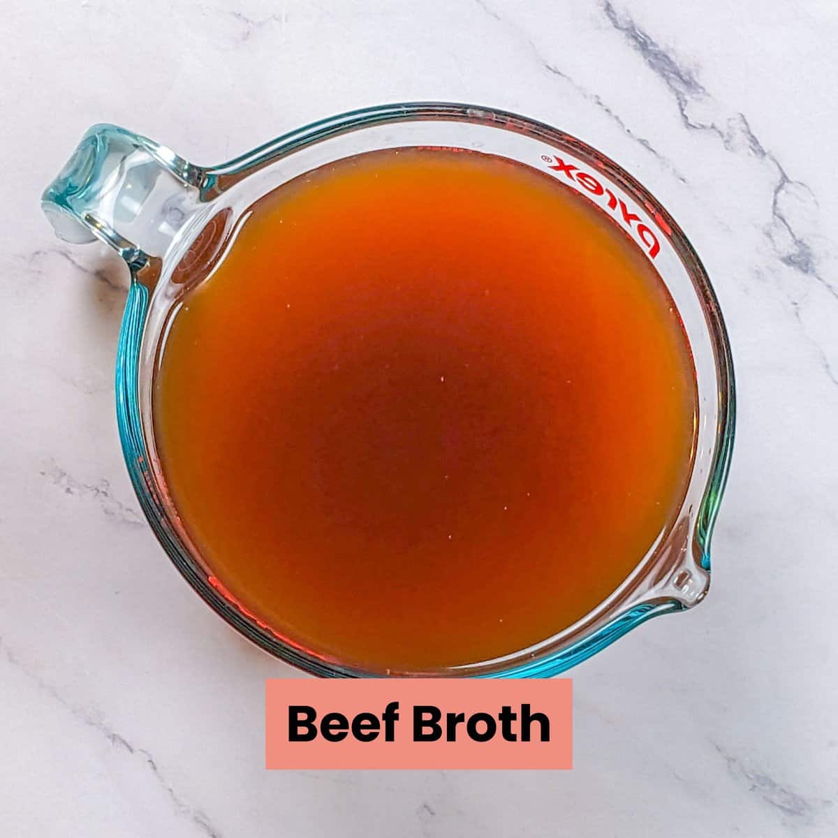 Rich beef broth in a clear measuring cup, showcasing savory depth and culinary appeal.