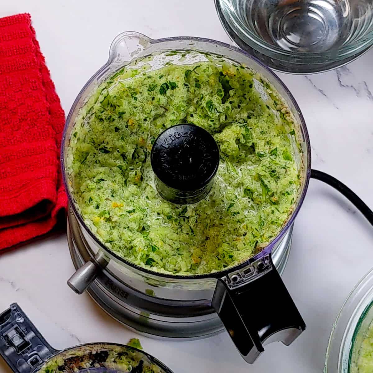 Fresh green herb mixture in a food processor for Spicy Beef Barley Stew preparation.