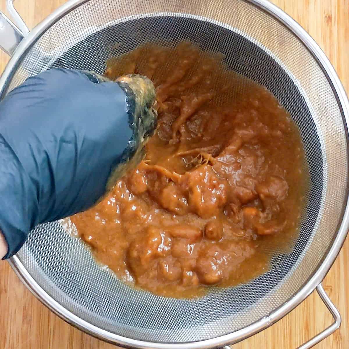 pulp massaged with gloved hands forcing it through the sieve