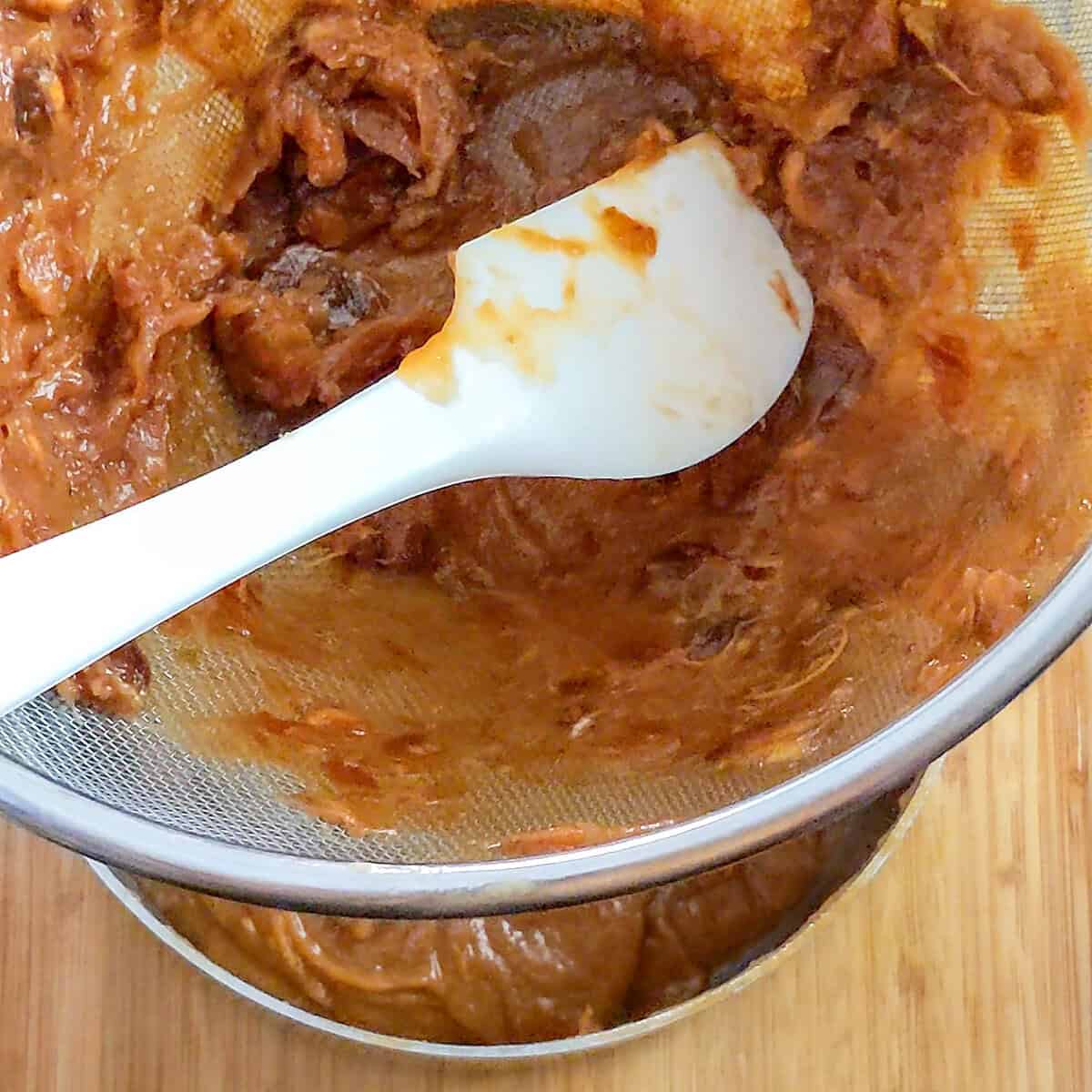 showing progress of pushing the tamarind pulp through the sieve with a silicone spatula.