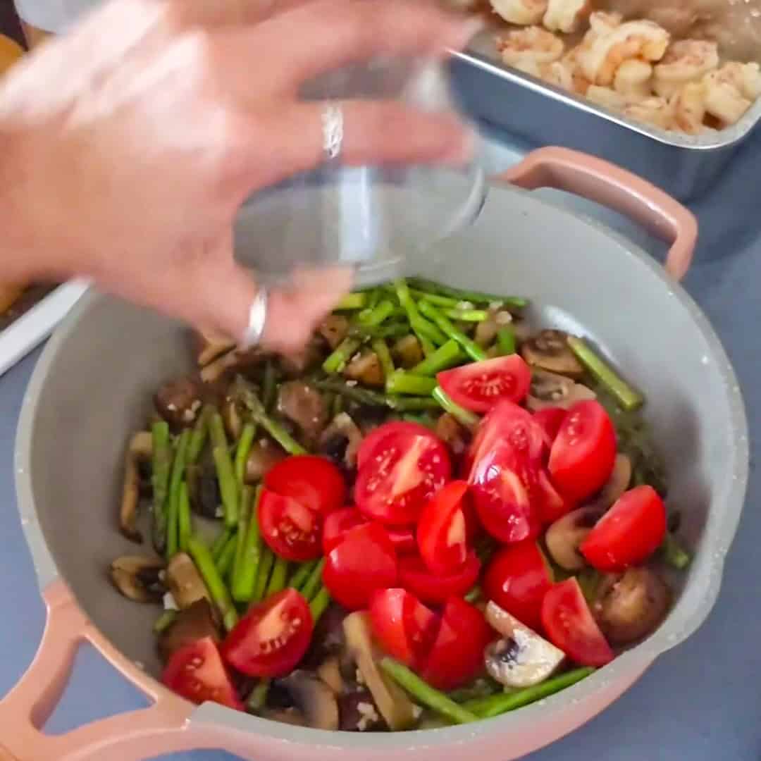 Colorful fresh vegetables and shrimp being prepared for Argentinian shrimp pesto pasta.