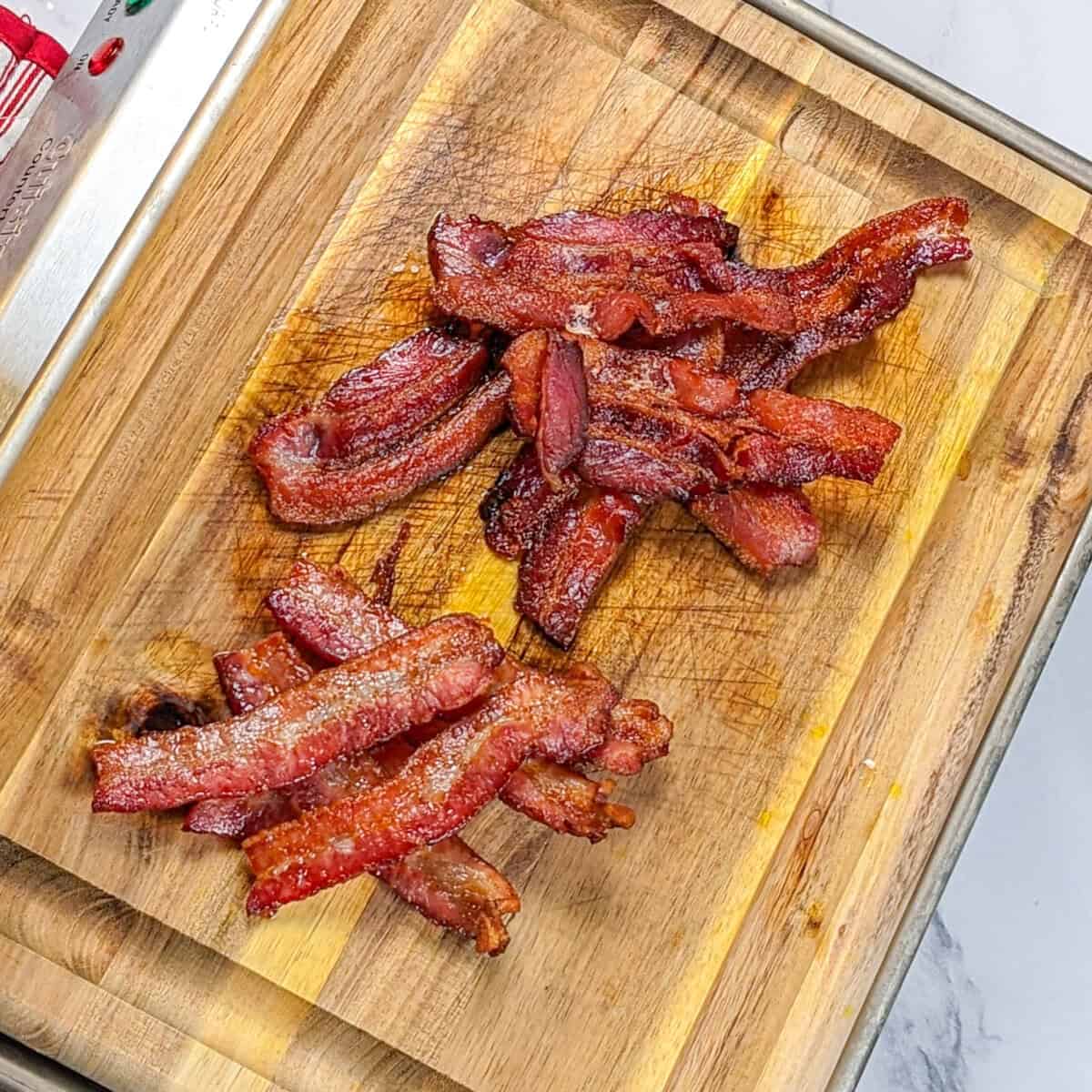 Crispy bacon strips arranged on a rustic wooden cutting board, perfect for breakfast lovers.