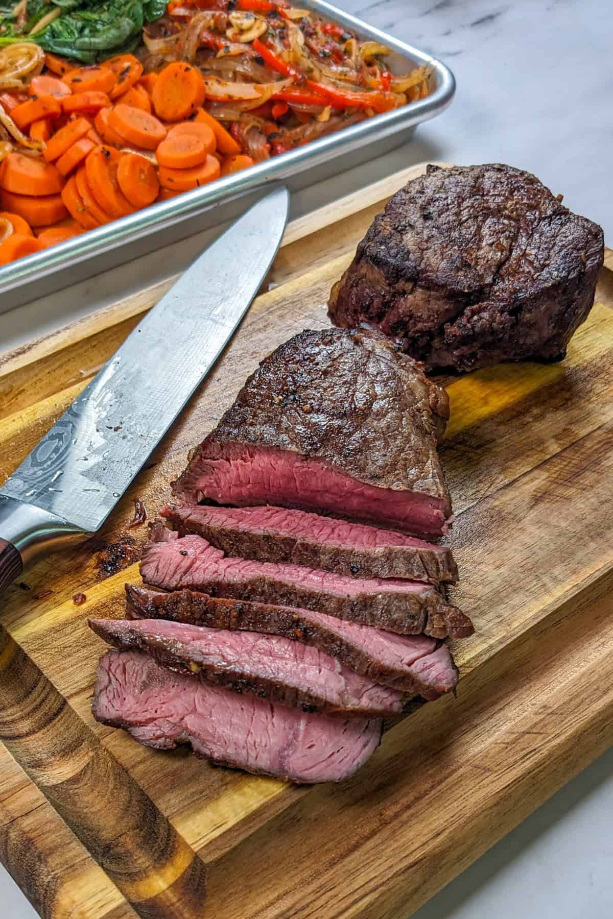 Tender top sirloin beef sliced on a cutting board next to a knife.