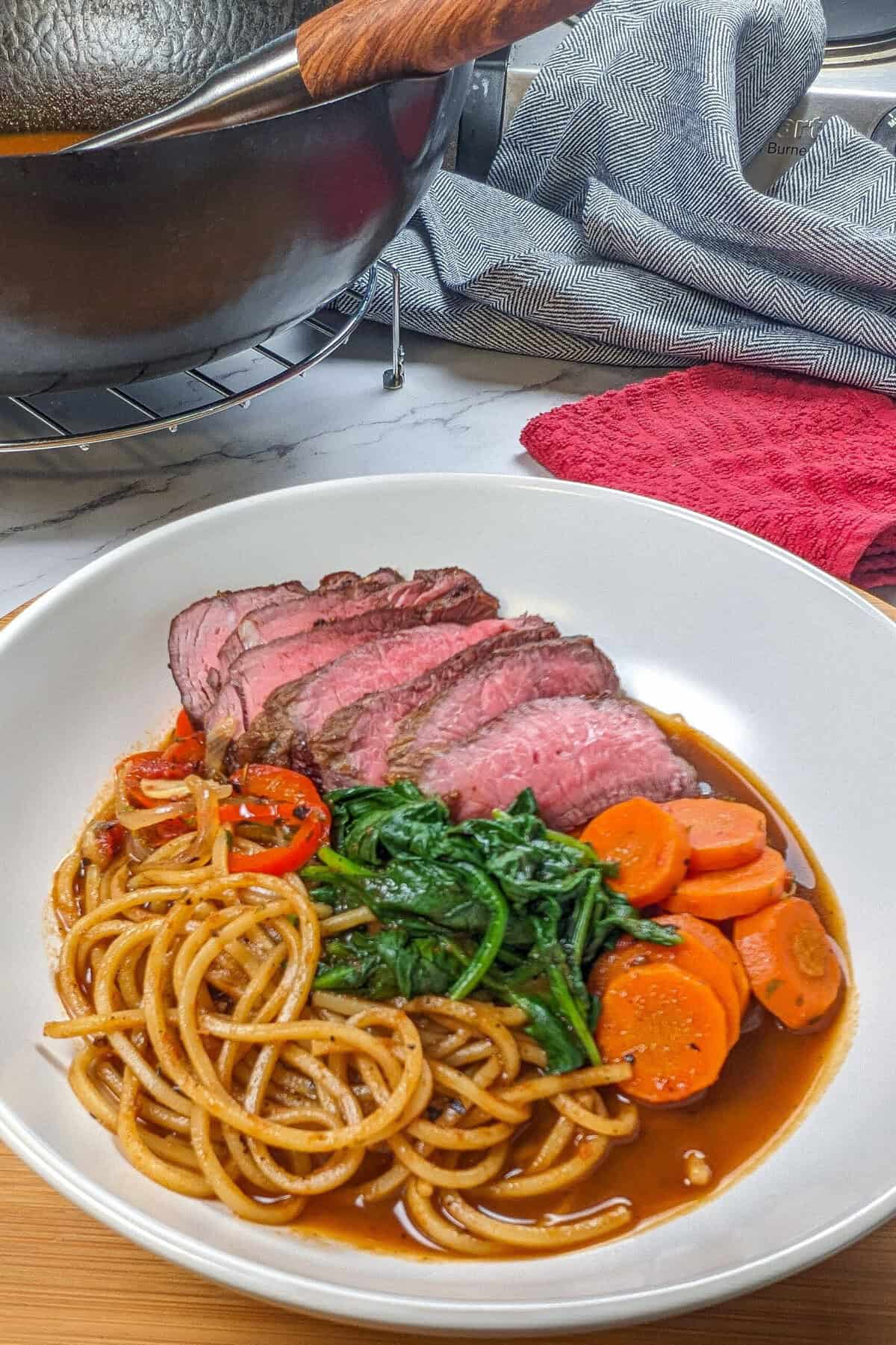 Colorful Caribbean beef noodle soup garnished with vibrant vegetables in a glossy broth.