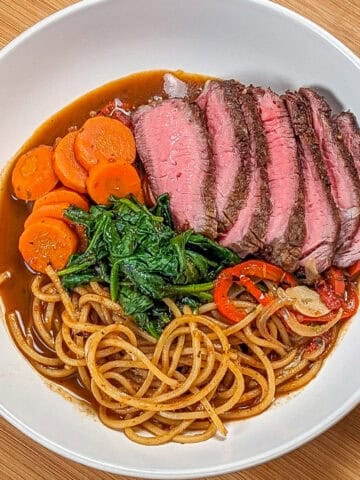 Vibrant Caribbean beef noodle soup with tender beef, fresh vegetables, and rich broth.