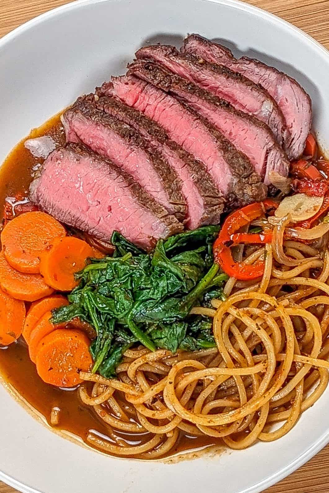 Delicious Caribbean beef noodle soup with vibrant vegetables and perfectly cooked beef slices.