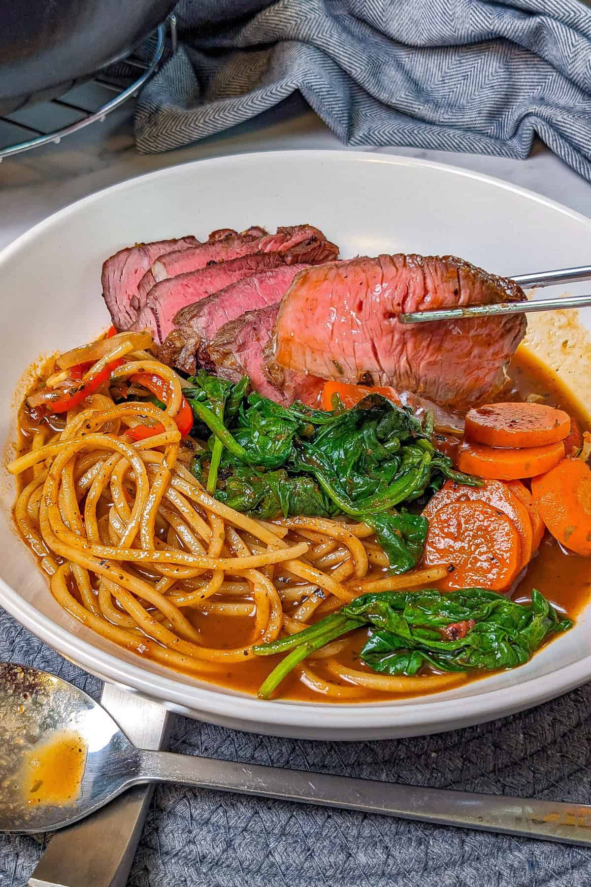 Caribbean beef noodle soup with vibrant vegetables in flavorful broth, perfect for cozy dining.