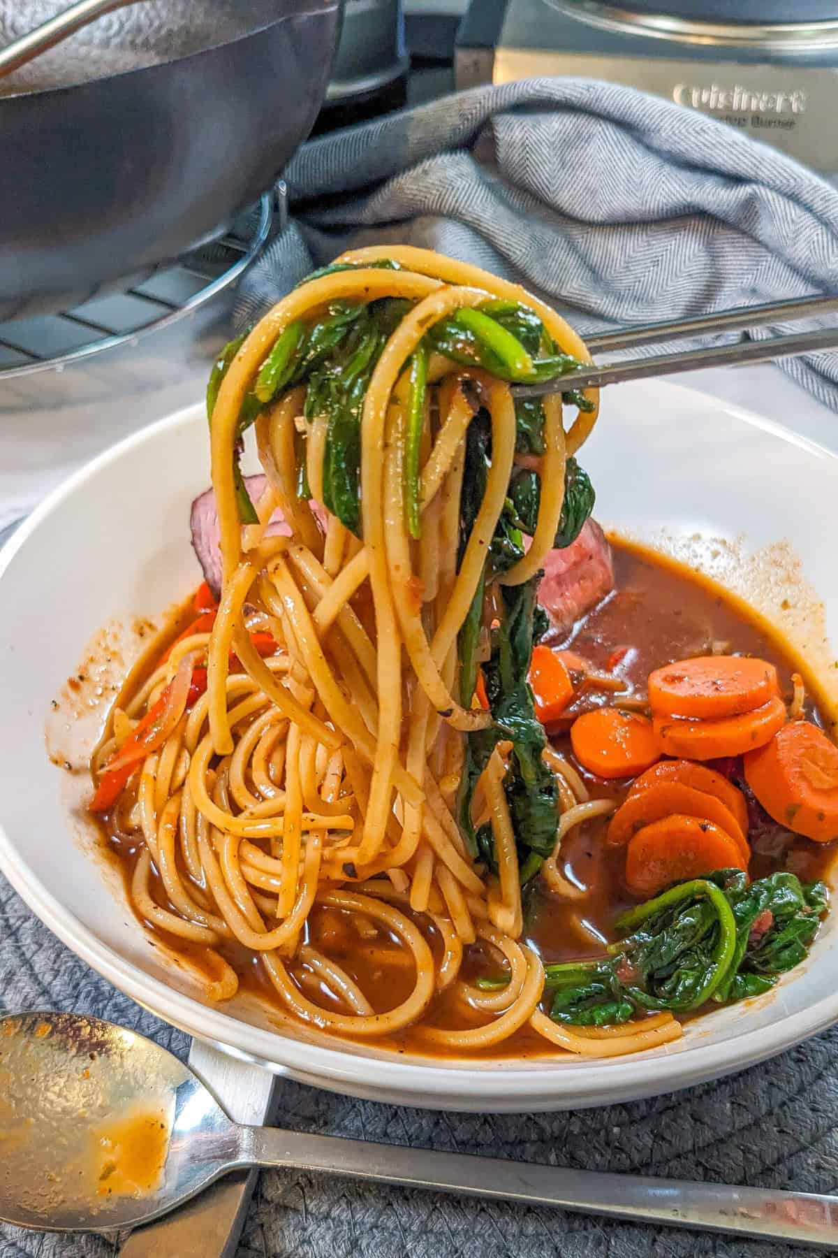 Caribbean beef noodle soup with vibrant vegetables in a savory, rich broth.