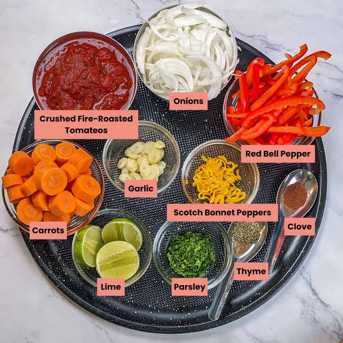 Colorful Caribbean beef noodle soup ingredients arranged aesthetically on a black tray.