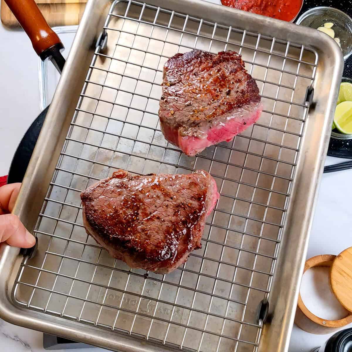 Delicious medium-rare steaks on a cooling rack, ready for Caribbean Beef Noodle Soup.