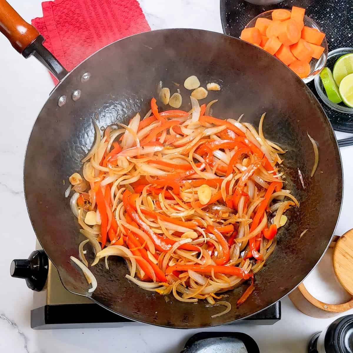 Vibrant vegetables sautéing in a wok for Caribbean beef noodle soup preparation.