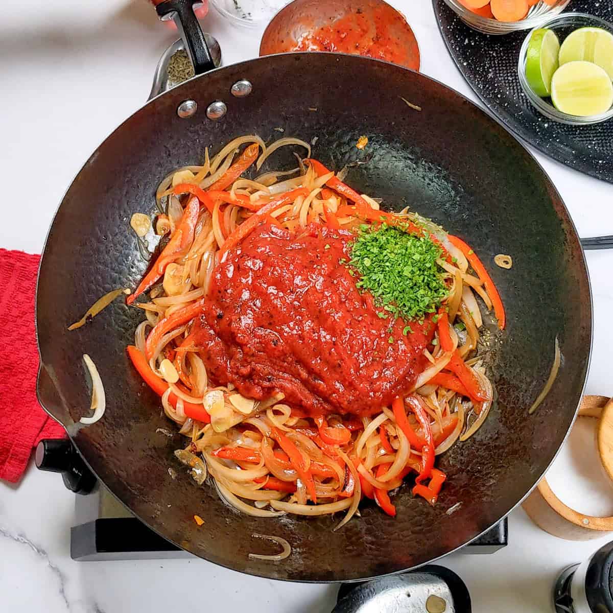 Vibrant Caribbean beef noodle soup being prepared with colorful vegetables and spicy sauce.