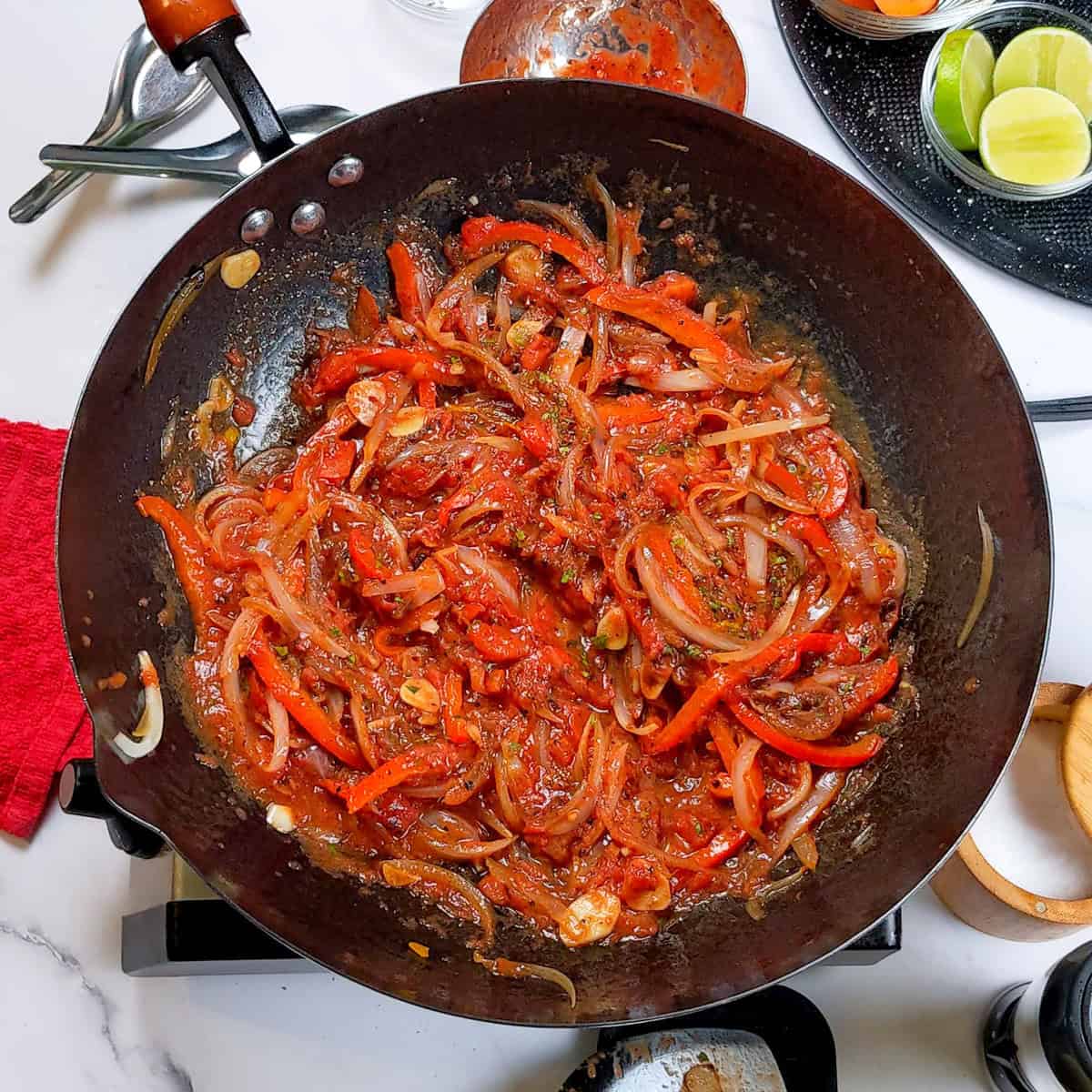 Colorful sautéed vegetables in a black wok for Caribbean beef noodle soup preparation.