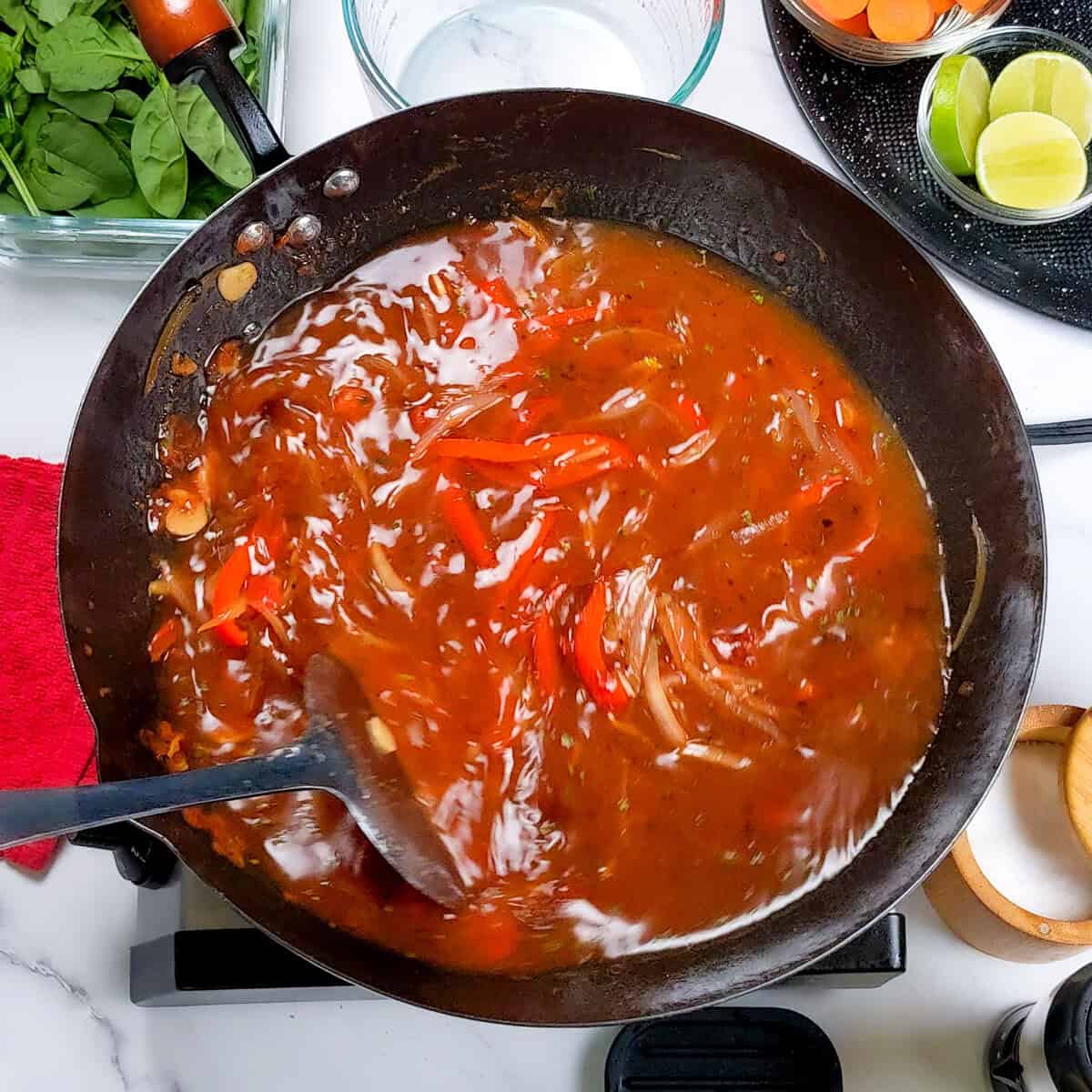 Vibrant Caribbean beef noodle soup simmering in a wok with fresh vegetables and spices.