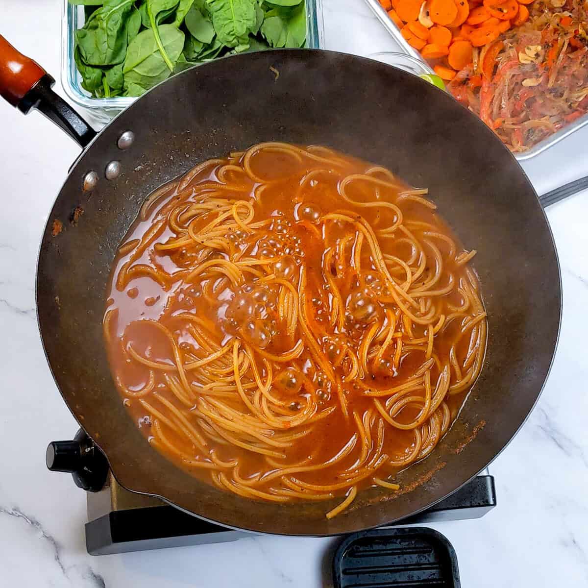 Caribbean beef noodle soup simmering with spinach and carrots for a nourishing meal.