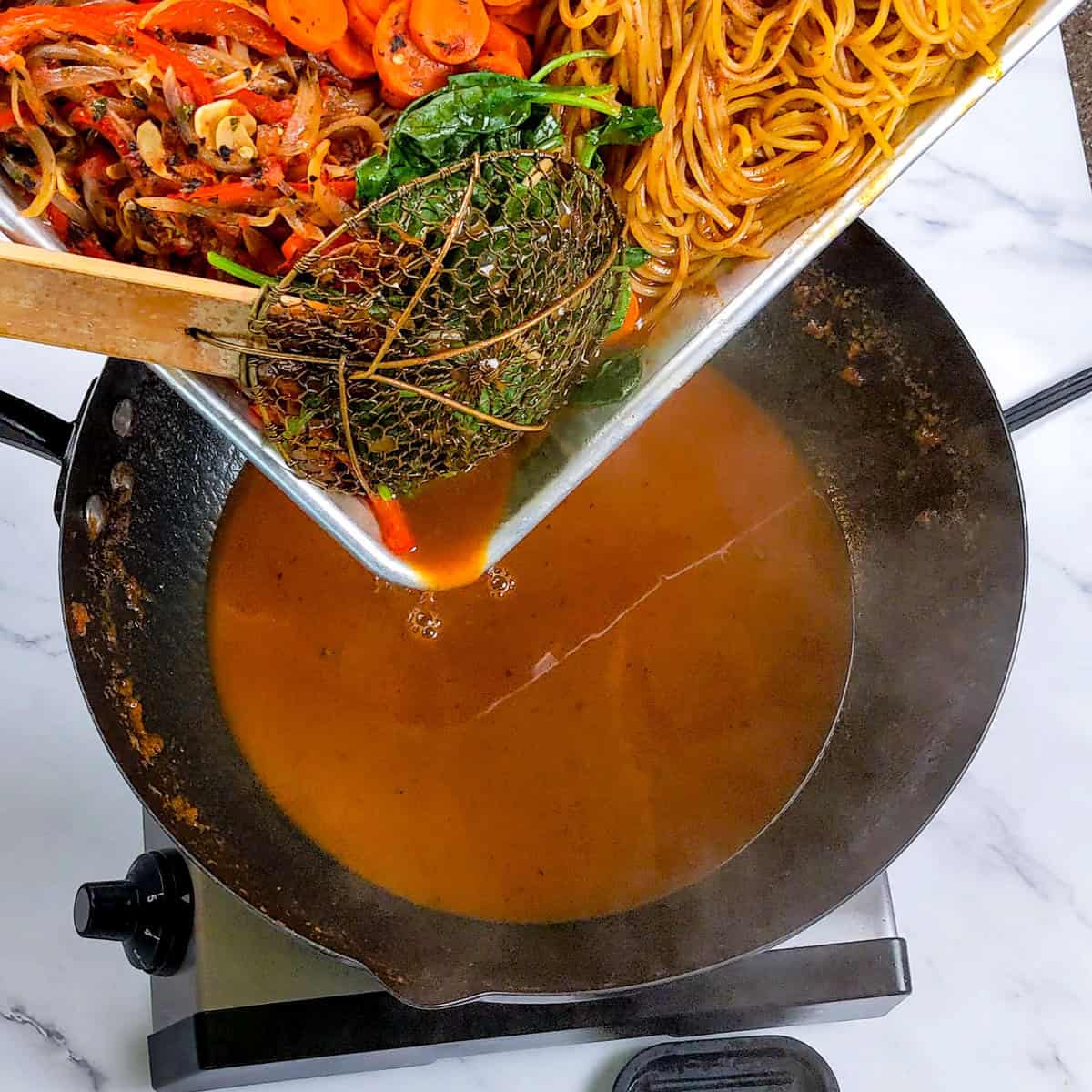 Vibrant Caribbean beef noodle soup ingredients being prepared in a modern kitchen.