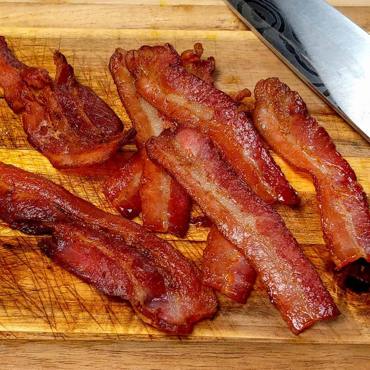 Crispy bacon strips on a wooden cutting board, perfect for breakfast or cooking.