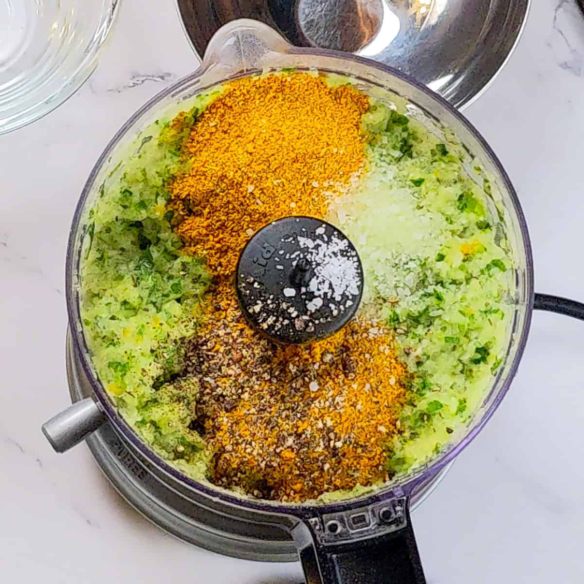 Chopped vegetables and spices in a food processor for healthy curry turkey meatball soup.