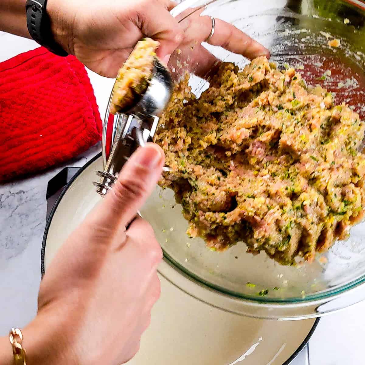 Hands preparing flavorful turkey meatballs for homemade curry soup.