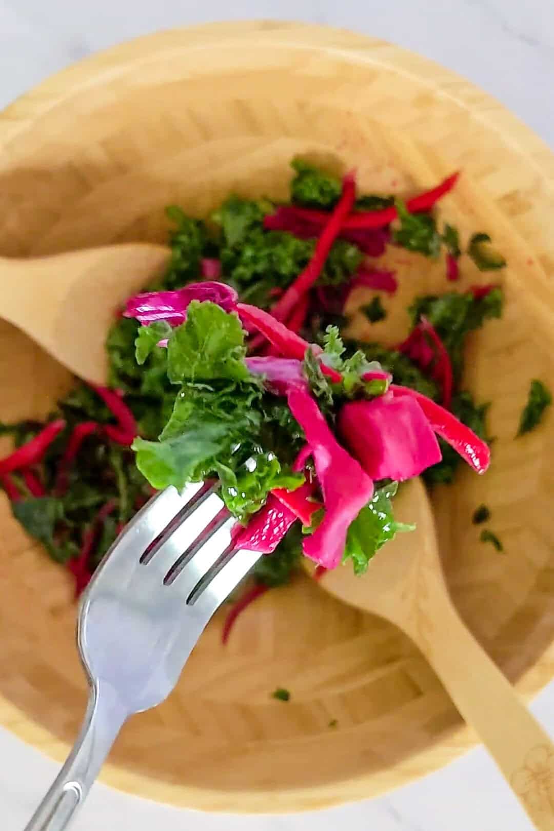 Vibrant massaged kale salad with pickled vegetables in a wooden bowl, ready to eat.